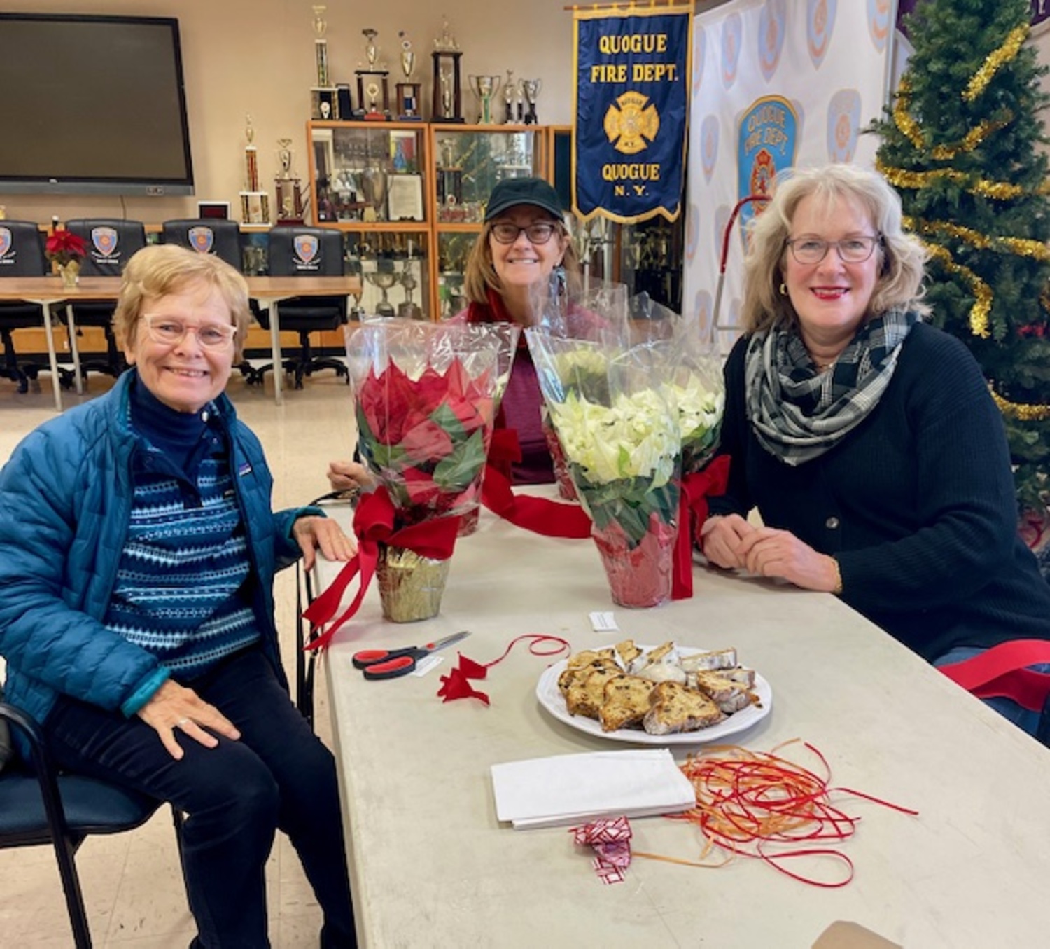 Westhampton Garden Club members met at the Quogue Firehouse for the club's annual holiday decorating workshop. Poinsetta plants festively adorned and wrapped with colorful ribbon were distributed to East End Hospice patients at the Kanas Center for Hospice Care and in homes throughout the East End. Among the participating members were, from left,  Roberta Young, Donna Vallone and Christine Tiberg. COURTESY WESTHAMPTON GARDEN CLUB