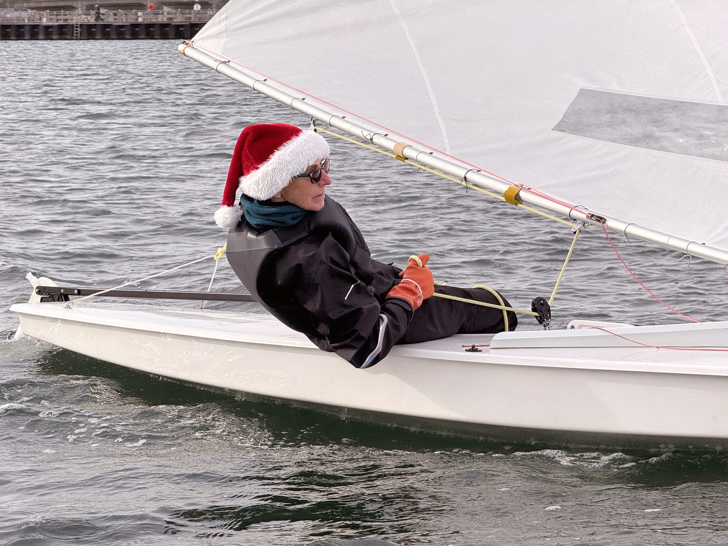 With little “body-ballast,” diminutive Joan Butler, a stalwart in the club’s women’s race circuit, is always seen hiking to windward to keep her boat on a reasonable angle of heel.  MICHAEL MELLA