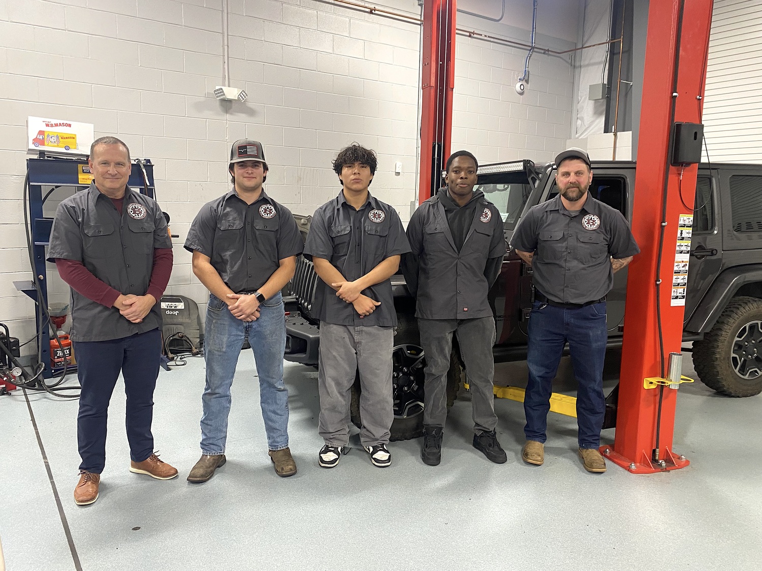 East Hampton automotive program instructors Peter Fletcher, on left, and Ted Page, on right, with seniors John Dunning, John Chillogalli and Josh Williams spoke about coursework inside the shop at the December 10 board of education meeting. EAST HAMPTON SCHOOL DISTRICT