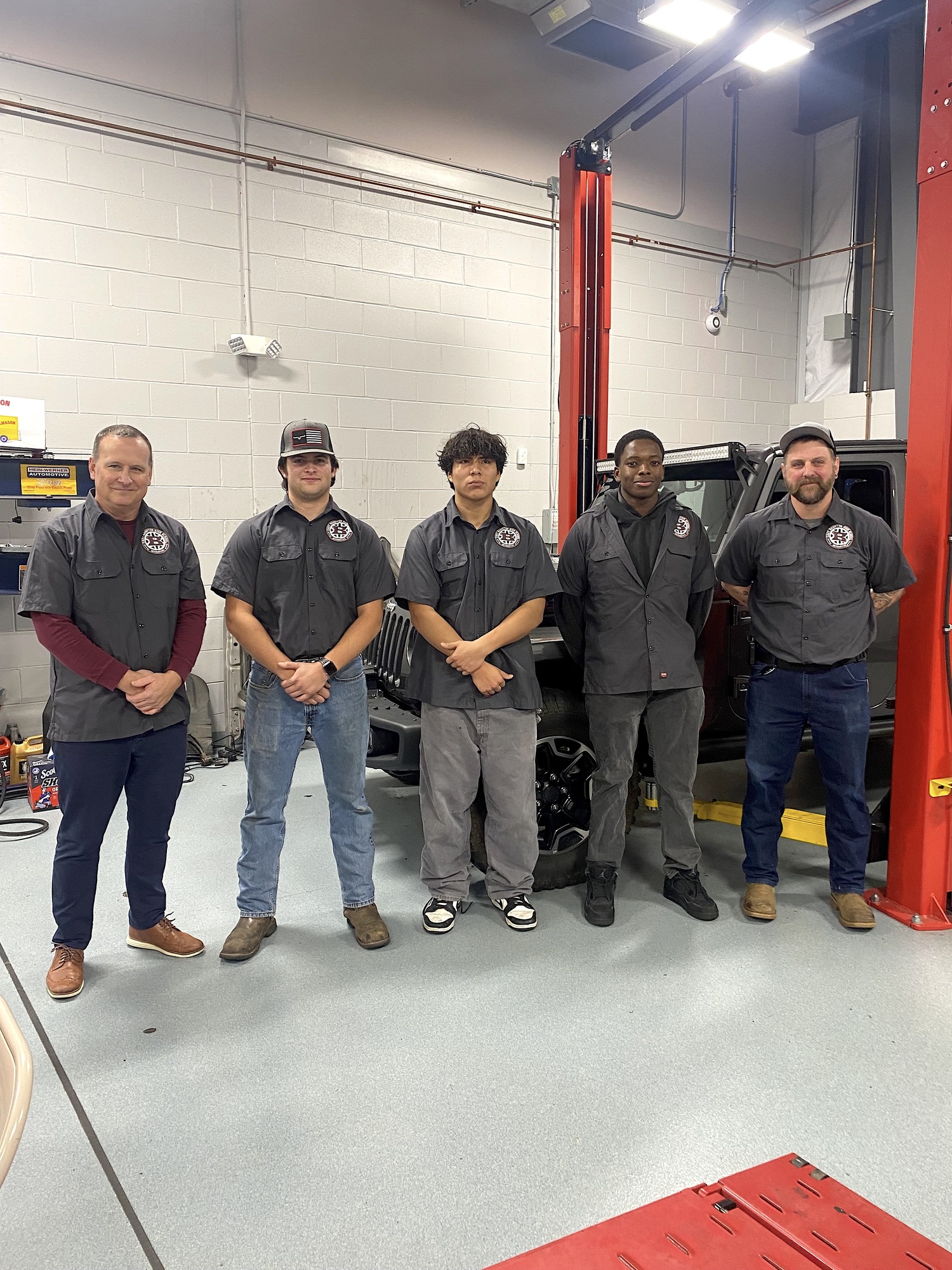 East Hampton automotive program instructors Peter Fletcher, on left, and Ted Page, on right, with seniors John Dunning, John Chillogalli and Josh Williams spoke about coursework inside the shop at the December 10 board of education meeting. EAST HAMPTON SCHOOL DISTRICT