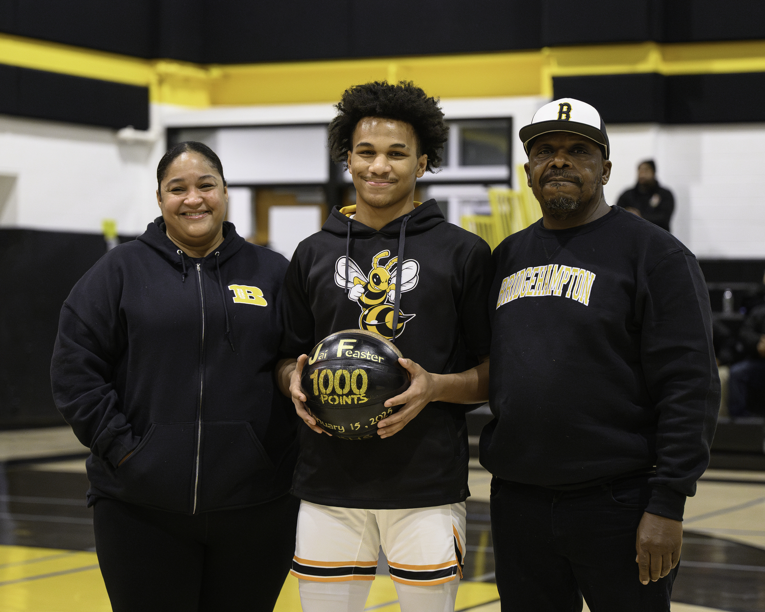 Bridgehampton junior Jai Feaster, flanked by his parents Vasthi and Michael, with his commemorative 1,000 career points basketball.   MARIANNE BARNETT