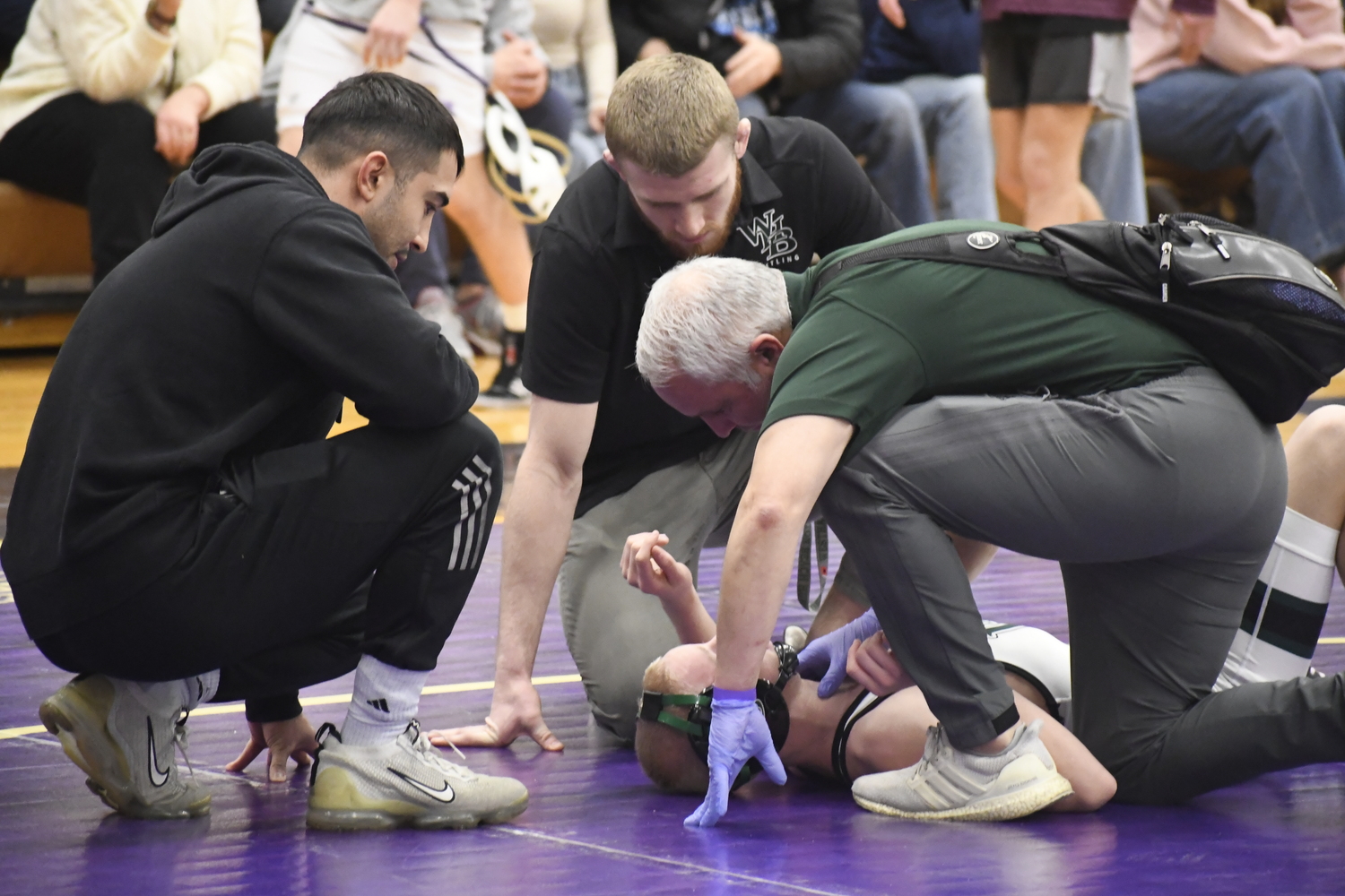 Westhampton Beach trainer Scott Leogrande and wrestling coaches check out Darren Cangelosi after he took an inadvertent shoulder to face in his finals match. DREW BUDD