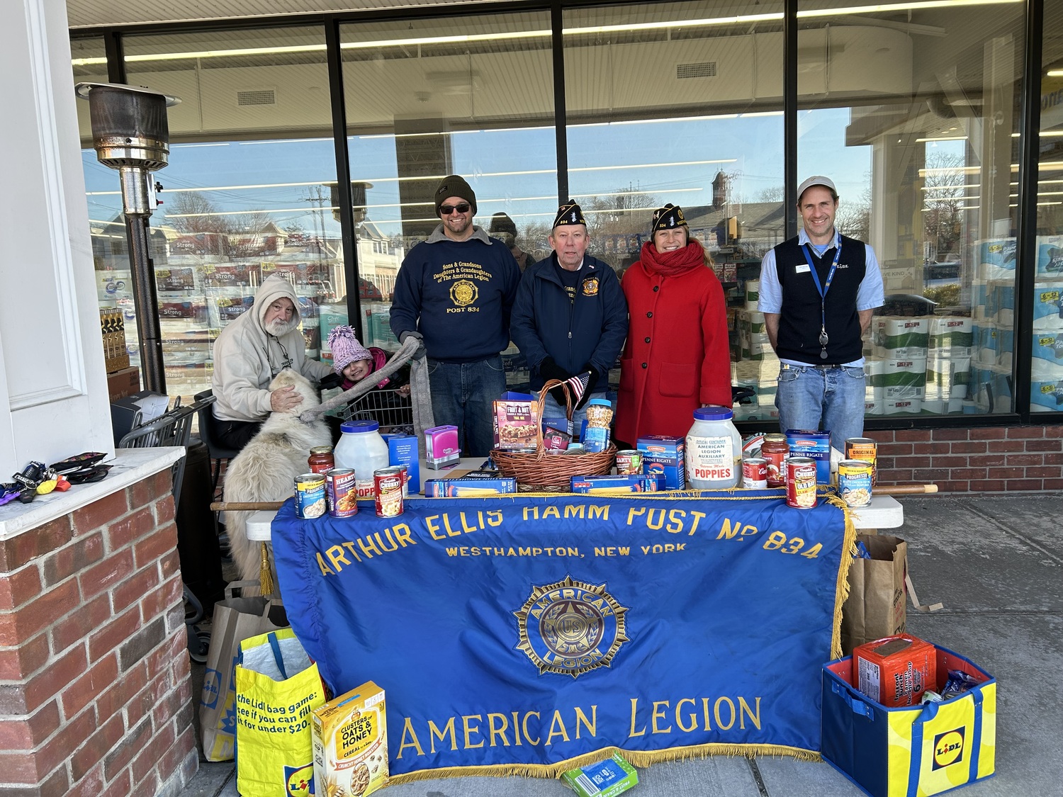 Westhampton American Legion Arthur Ellis Hamm Post #834 collected donations outside the Lidl Supermarket for the local food pantry. In just a few hours, roughly $2,000 worth of food was donated for those in need. Volunteers included, from left, Paul Haines, Alora Atkins helping her dad Matt, Tom Quinn, Post Commander Lisha Terry,  with Lidl manager Deric Windus. COURTESY GEORGE MOTZ