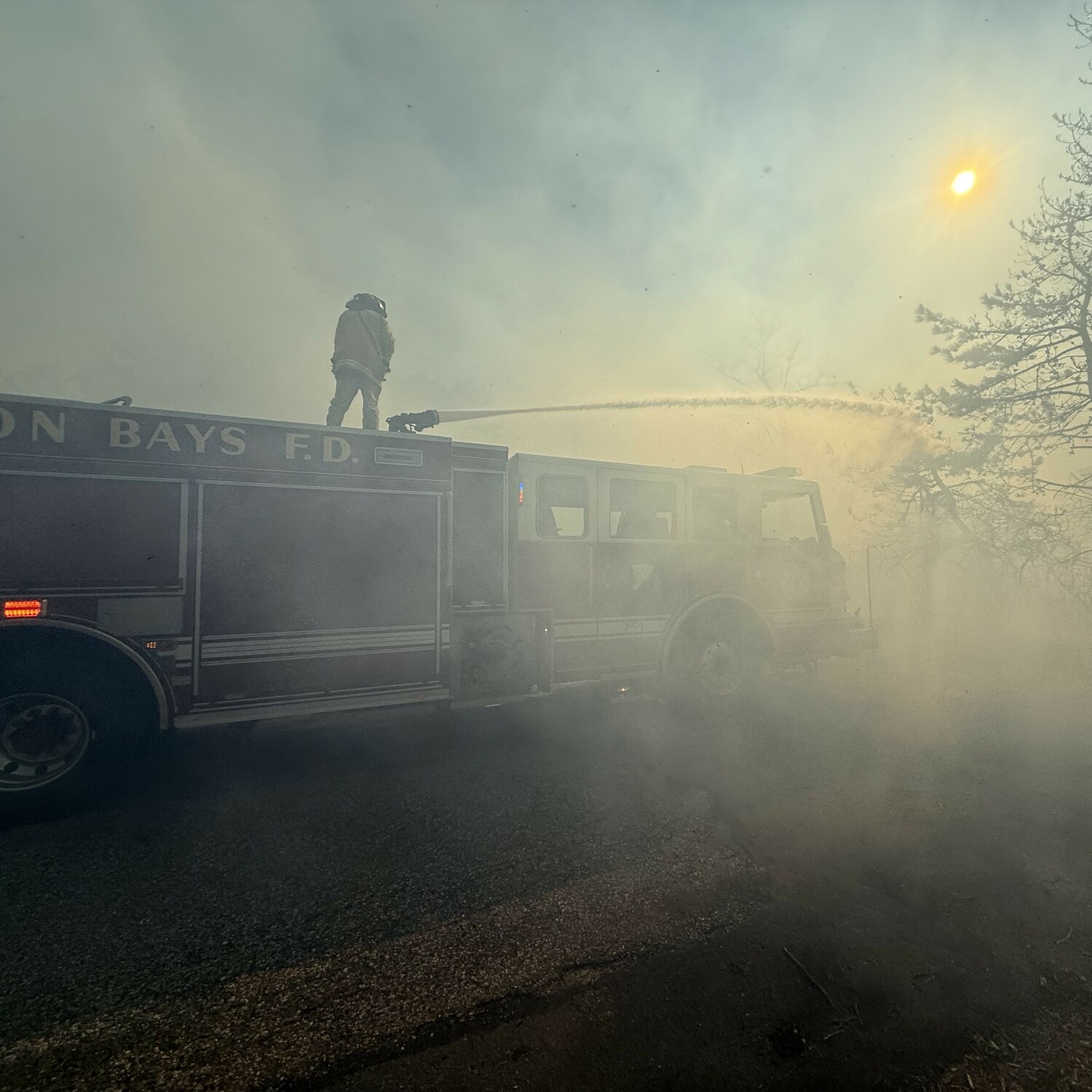 Hampton Bays Fire Department firefighters battle flames around the East End Hospice offices on Saturday. HBFD