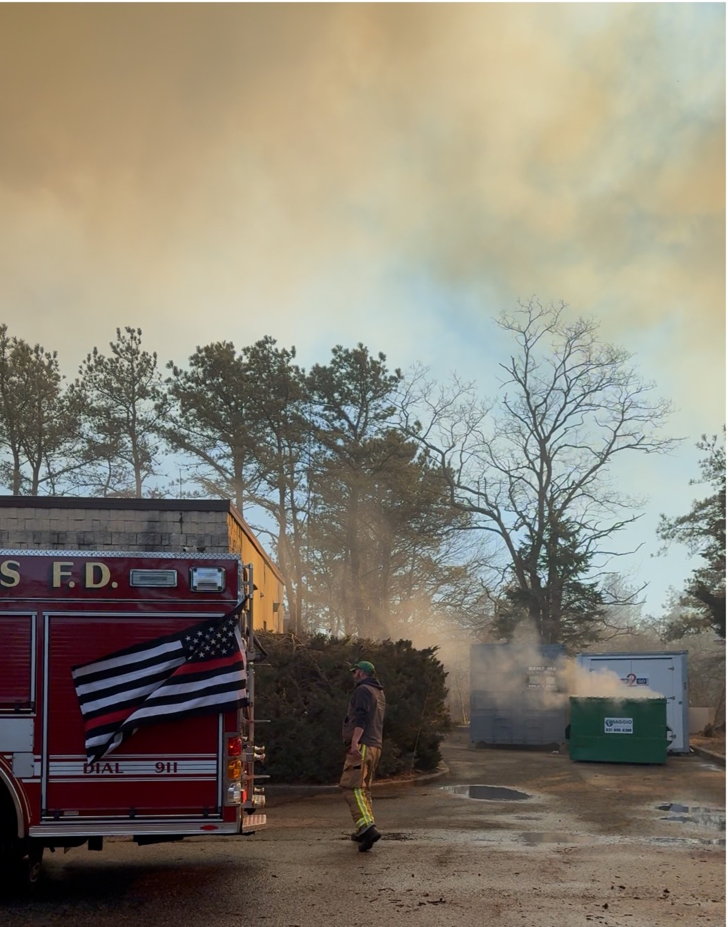 Hampton Bays Fire Department firefighters battle flames around the East End Hospice offices on Saturday. HBFD