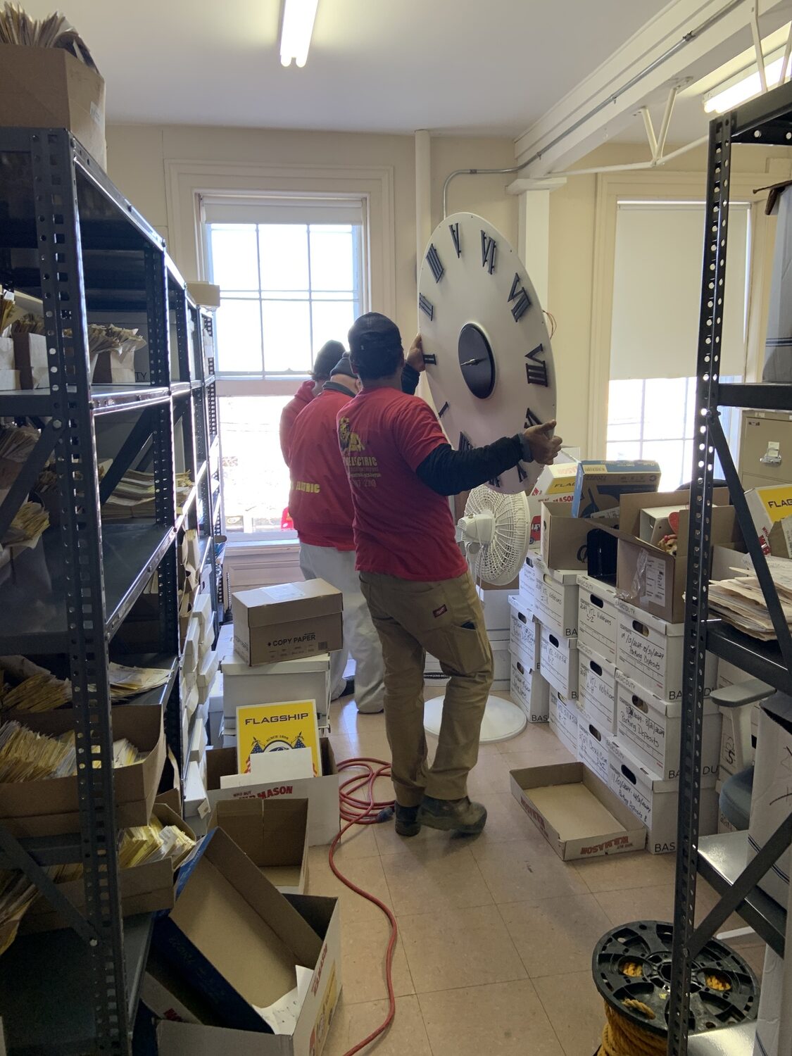 Workers with Leo's Electric prepare to install the face of the new clock. STEPHEN J. KOTZ