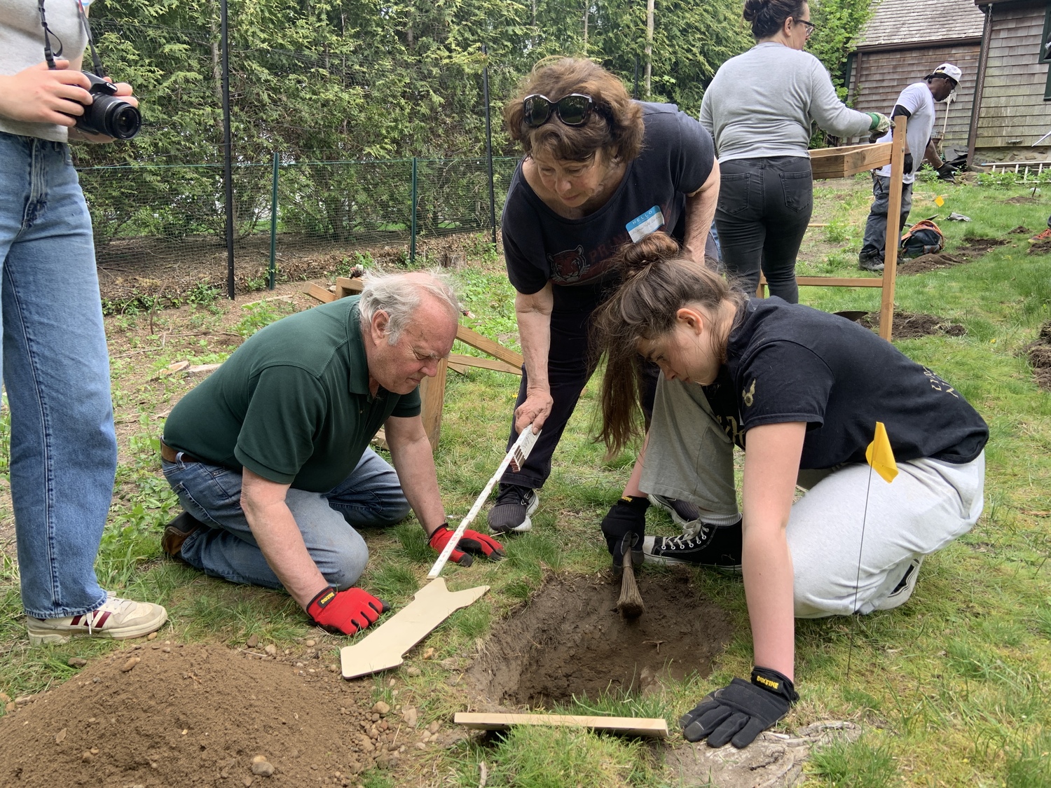 From left, Zach Studenroth, president of the Sag Harbor Historical Museum, archeologist Jo-Ann McLean and Isla McLean examine one of several holes dug behind the Annie Cooper Boyd House for artifacts. STEPHEN J. KOTZ