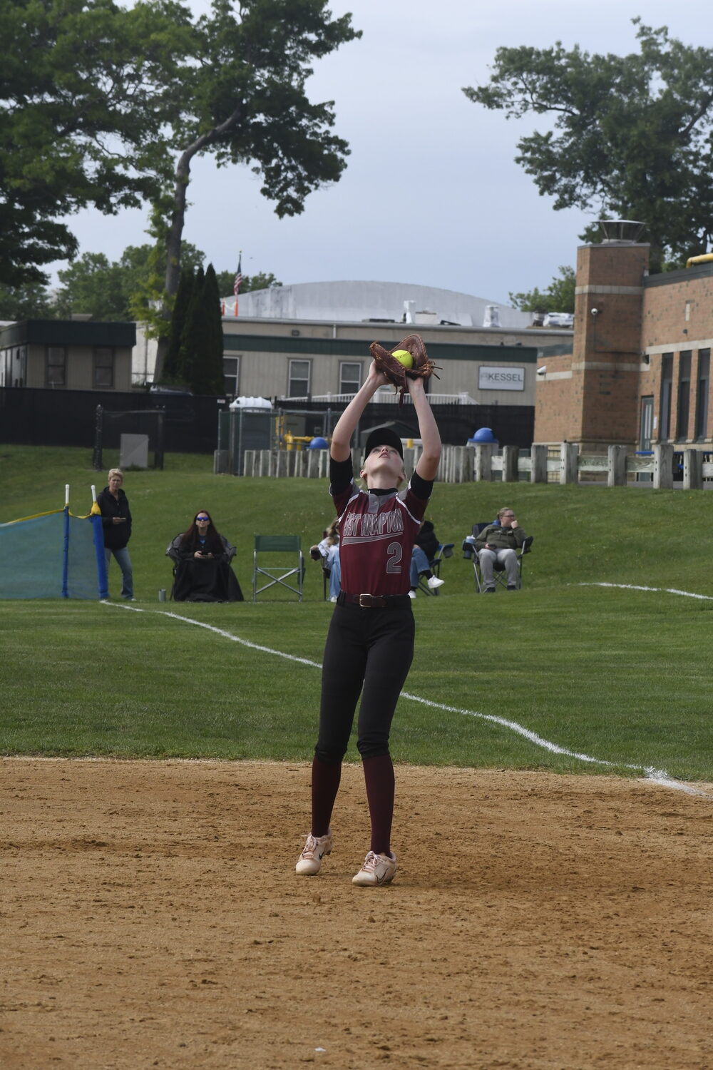 East Hampton first baseman M.J. VIckers squeezes a pop fly for an out.   DREW BUDD