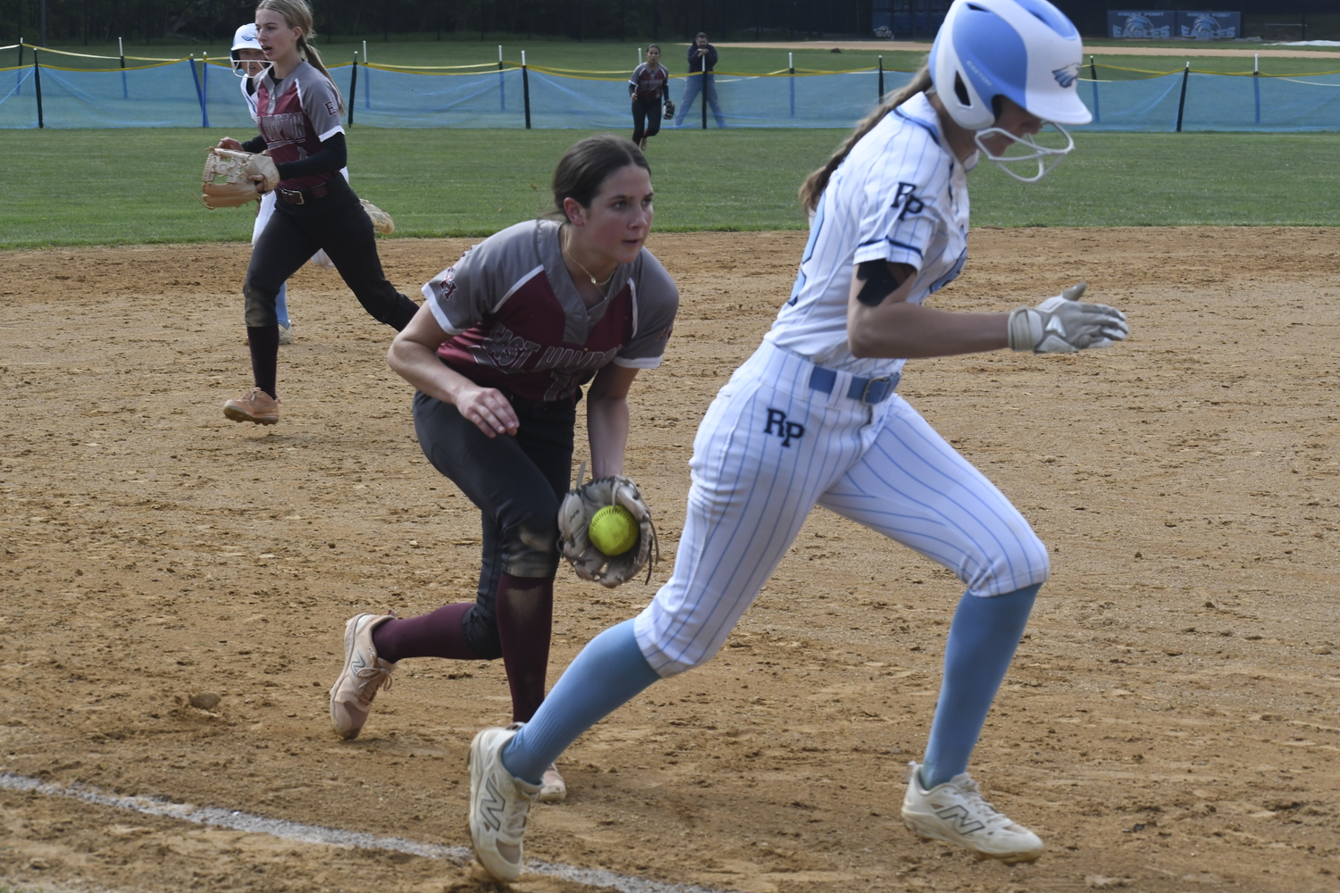 East Hampton third baseman Alexa Schaffer fields a ground ball while contending with the runner heading home, which she got out.  DREW BUDD