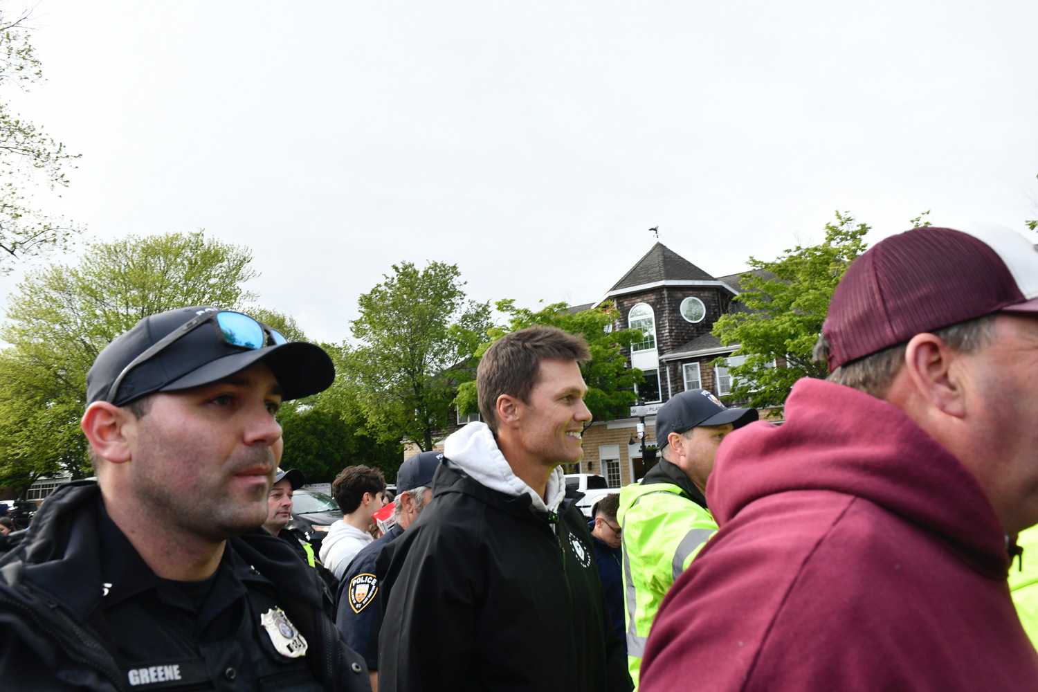 Tom Brady is escorted, by East Hampton Village Police and the East Hampton varsity football team, back to the CardVault storefront.   DANA SHAW
