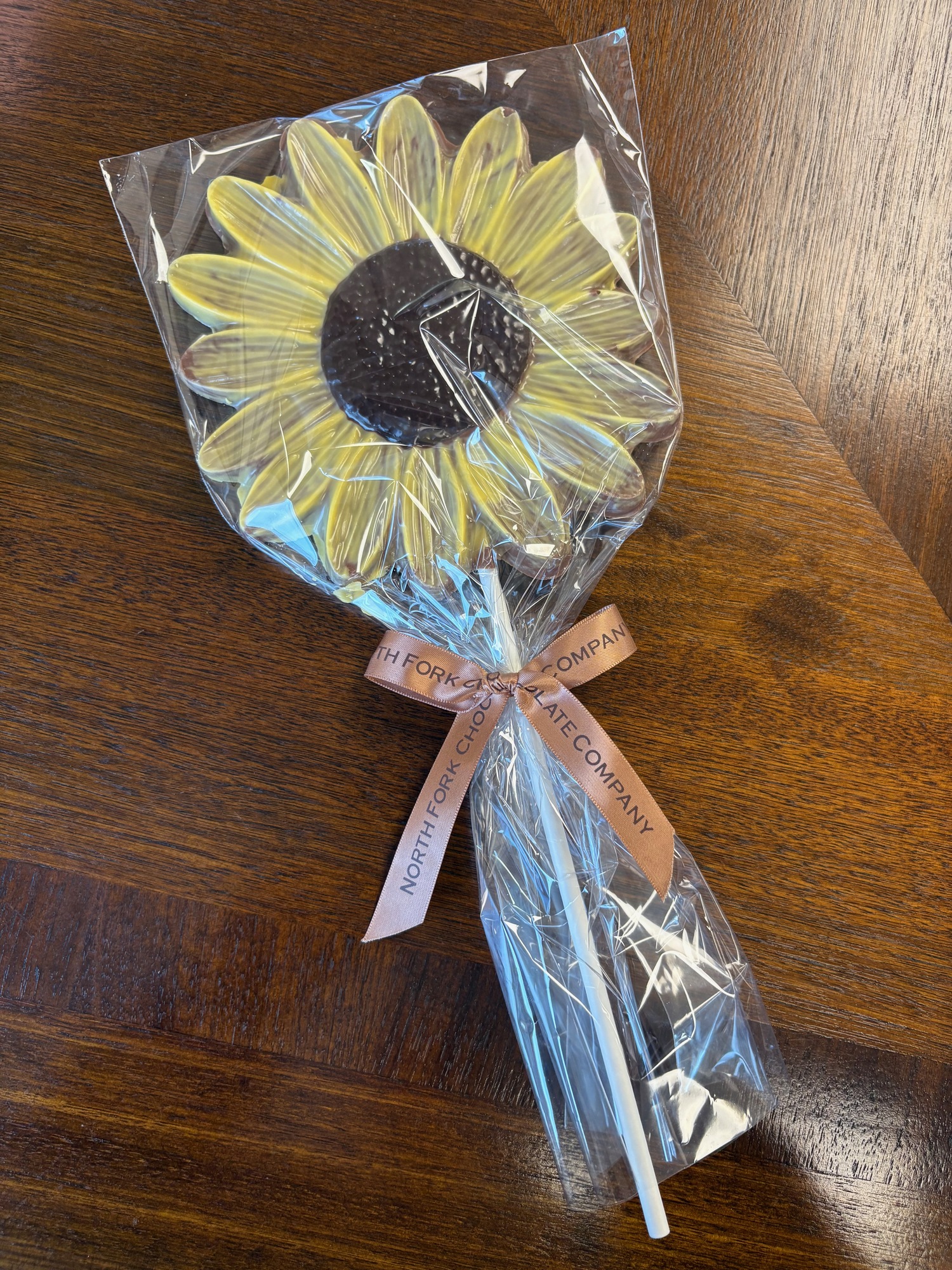 A giant lollipop shaped like a big sunflower spans about the size of a person’s opened hand.