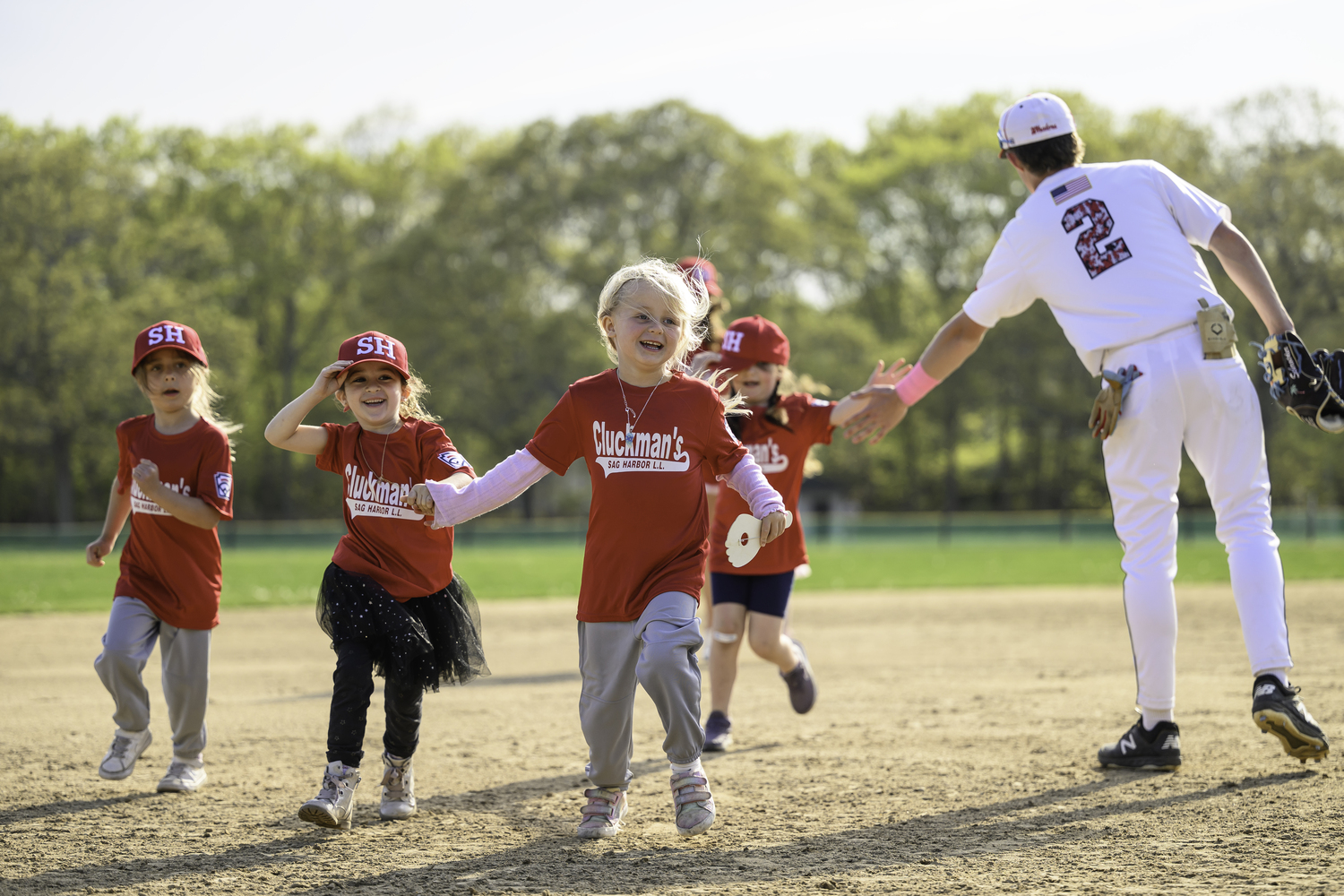 Members of the Cluckman's team of the Sag Harbor Little League run the bases and get a high-five from varsity baseball player Spencer Cavaniola.   MARIANNE BARNETT
