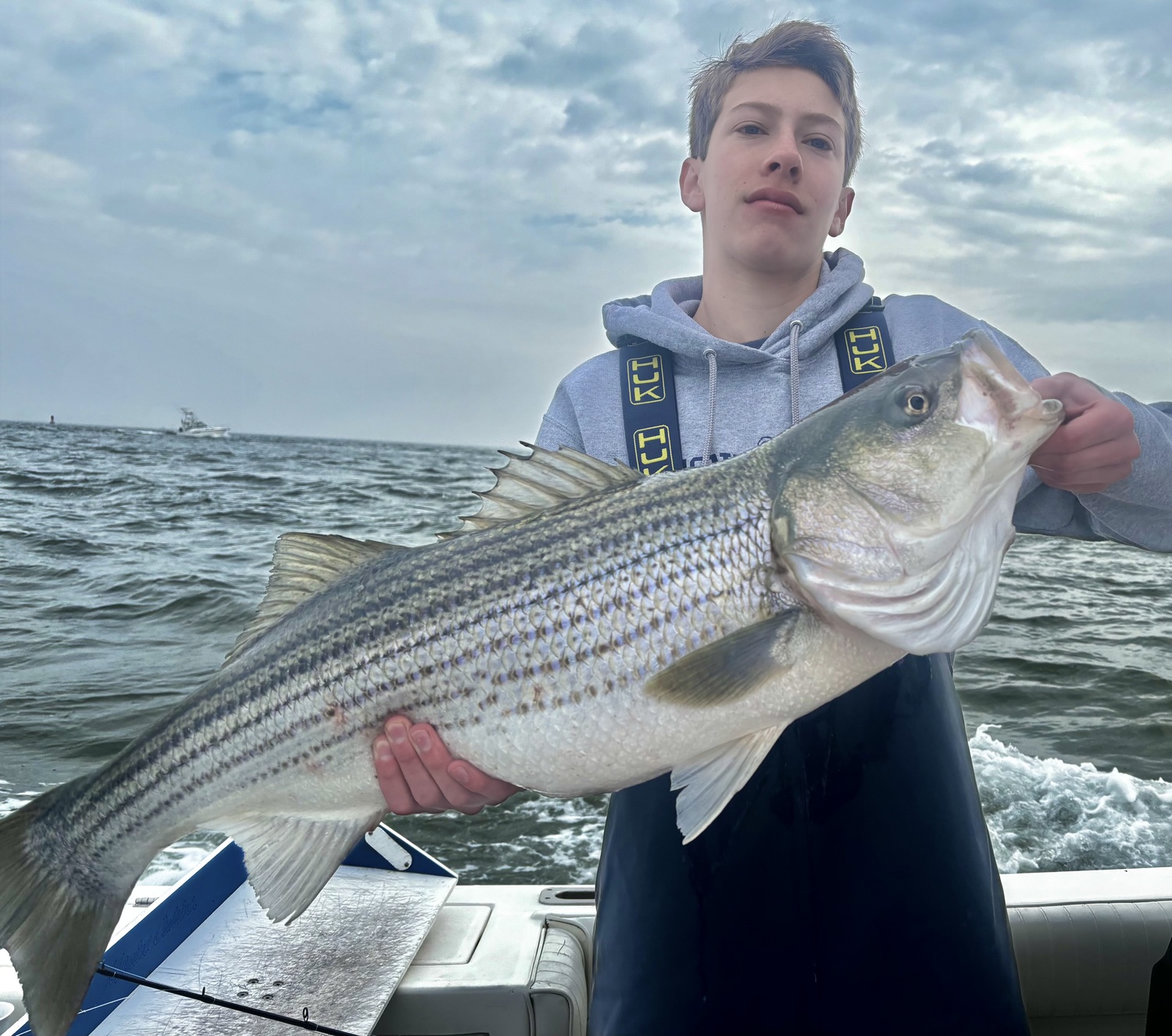 Andrew Dehler and an over-slot striped bass he caught and released off Orient Point recently. KEVIN DEHLER