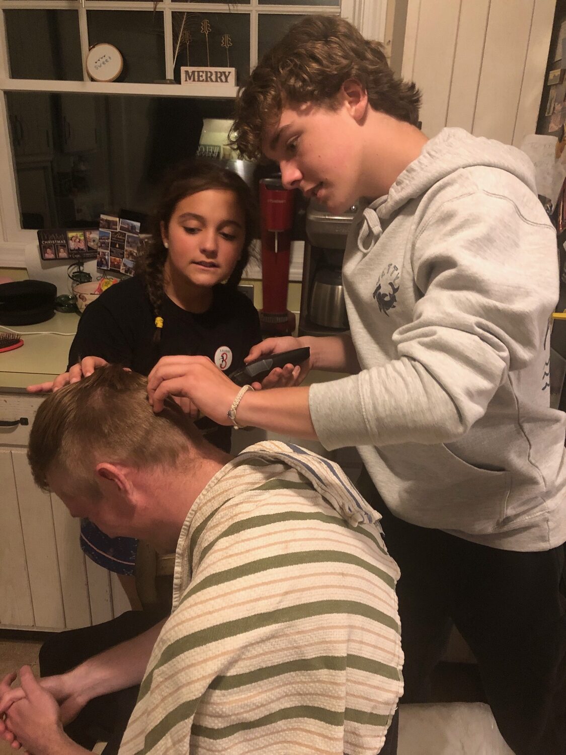 Addison and Mason Stevens giving Sean Collins a haircut during the Covid lockdown. Collins coached the Stevens siblings and was their neighbor at that time, spending a lot of time with the family.