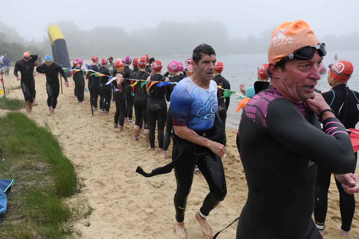 Triathletes make their way out of the water at Lake Montauk while others wait to get in at the Robert J. Aaron Mighty Montauk Triathlon on Saturday morning.   DOUG KUNTZ