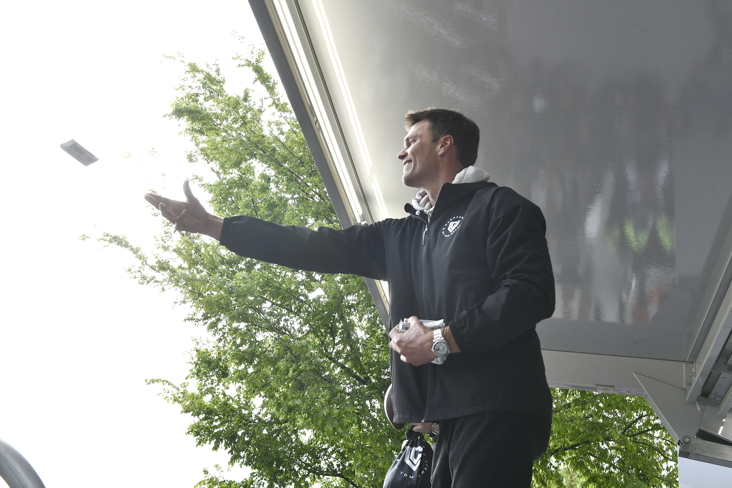 Former NFL quarterback Tom Brady passes out sports cards from the stage in Herrick Park in East Hampton on May 22.  DANA SHAW