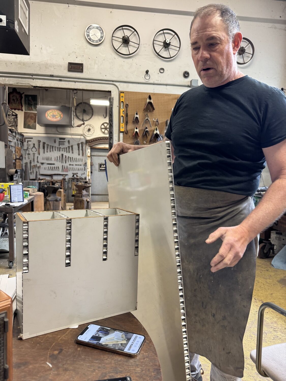 James DeMartis in his studio with components of the aluminum inserts he fabricated to hold the refurbished brass doors in the new Sagaponack Post Office. PETER BOODY PHOTO