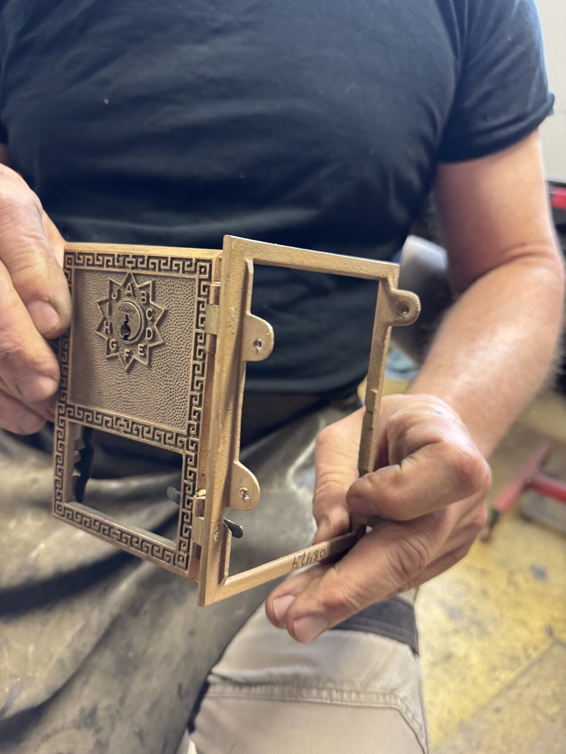James DeMartis holds a refurbished antique brass postal box door. PETER BOODY PHOTO