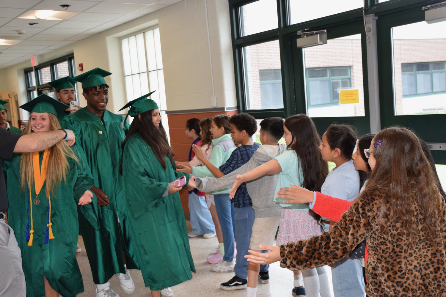 Wearing their green graduation gowns, members of the Westhampton Beach High School Class of 2025 marched through the halls of their former elementary school on June 16. They reminisced about their early school days and provided inspiration to current students. As they took the traditional senior walk, the elementary students cheered, clapped and held up signs of congratulations. COURTESY WESTHAMPTON BEACH SCHOOL DISTRICT