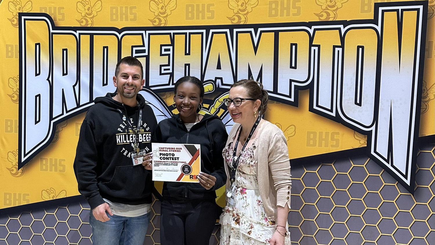 School counselor Ryan Barker with student Indya Cherry, first-prize winner  in the Community Connections category for the photo “Thankful Hearts, Helping Hands: A Community Food Drive,” alongside Hamra Ozsu. COURTESY BRIDGEHAMPTON SCHOOL DISTRICT