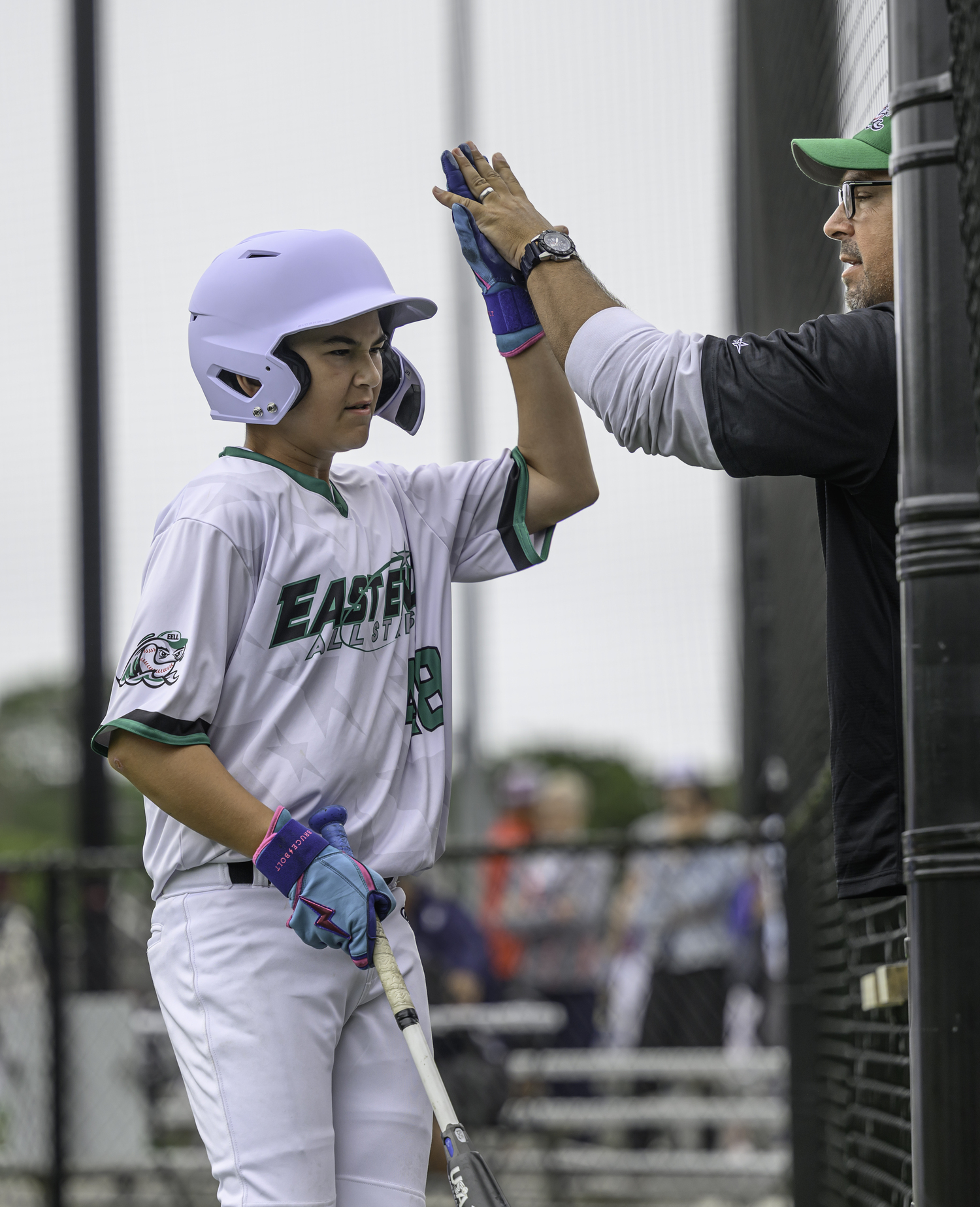 George Monsour high-fives his coach after scoring a run.  MARIANNE BARNETT