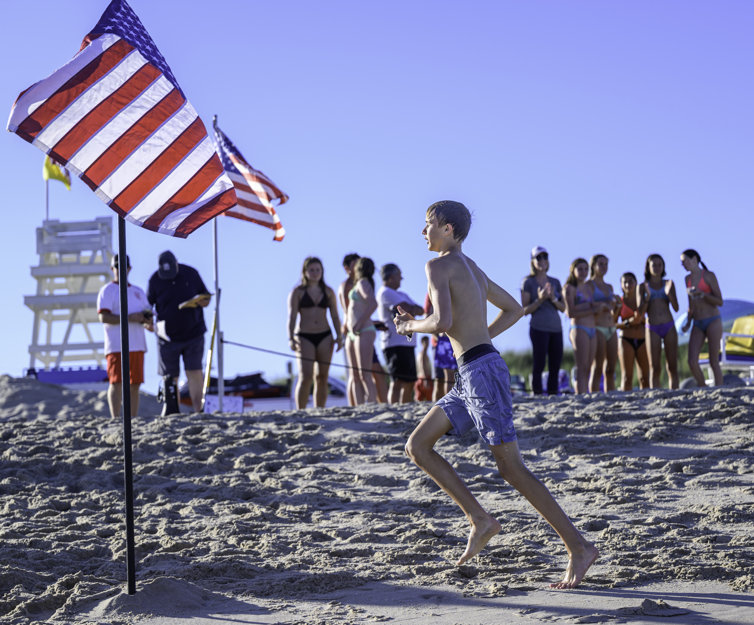 A participant crosses the finish line with applause from other participants.  MARIANNE BARNETT
