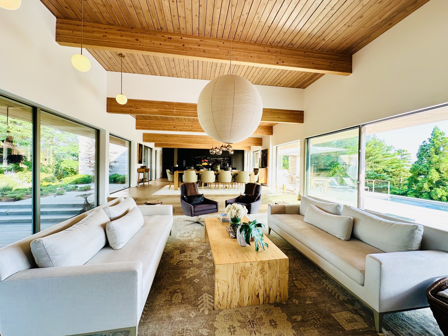 The living-dining-kitchen area, open concept with an emphasis on the views on both sides, outdoor aviary and views of Shinnecock Bay. The light fixture is a Noguchi ball. OZ VAN ROSEN