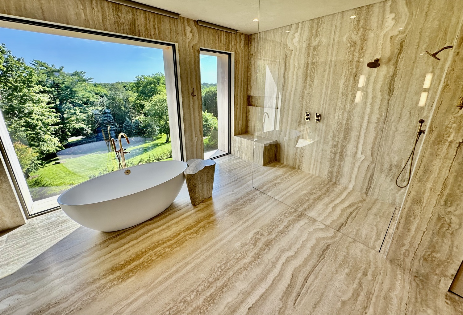 The line motif continues in the master bath with meticulously vein matched alabaster travertine to give the illusion of a room cut out from solid stone. OZ VAN ROSEN