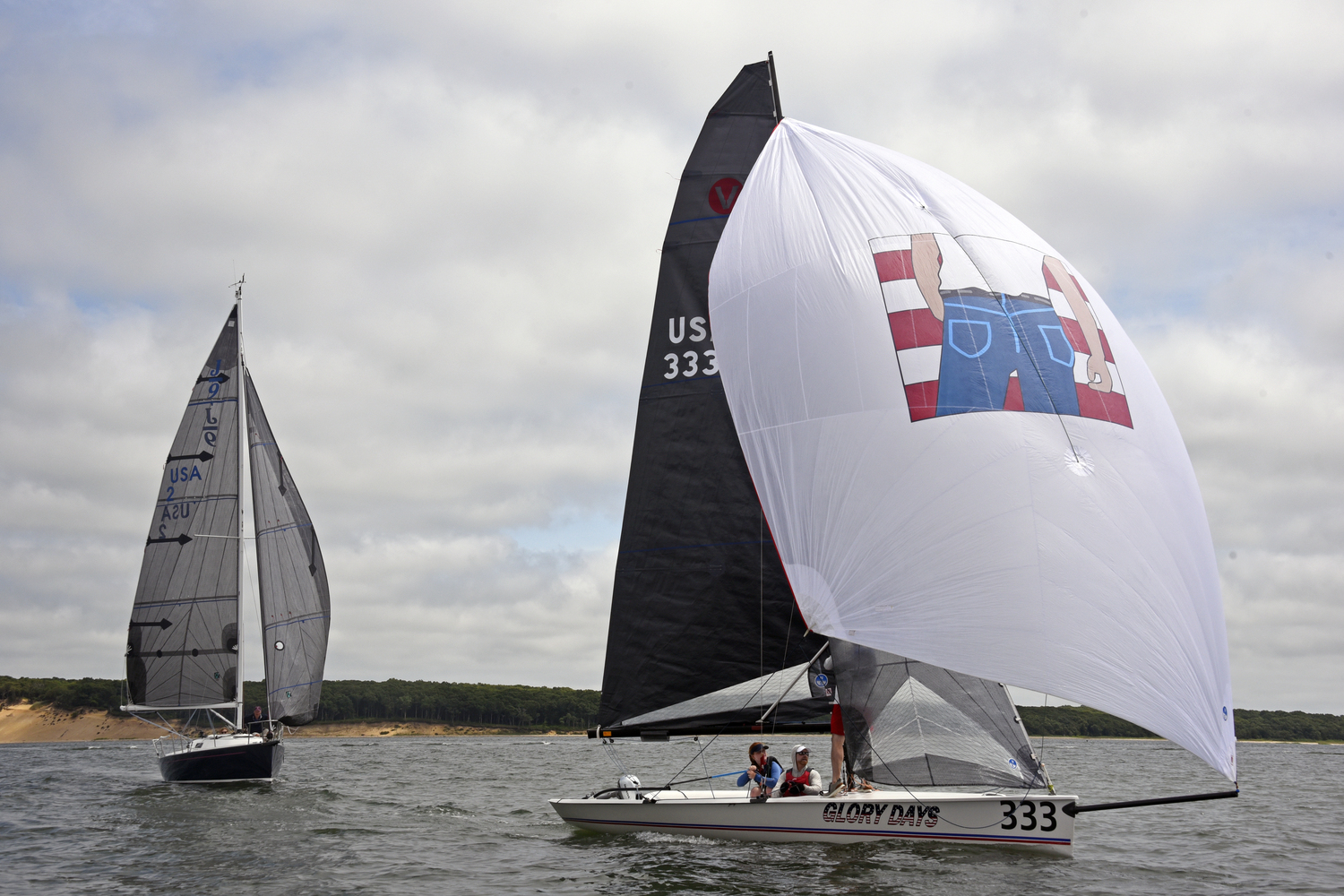Peter Beardsley exhibits a sense of humor when it comes to his spinnaker logo designs! Here Venetia Satow has taken over the tiller while Peter, standing, fine-tunes the spinnaker. Off their stern is a J-9, Inda’s Way. MICHAEL MELLA