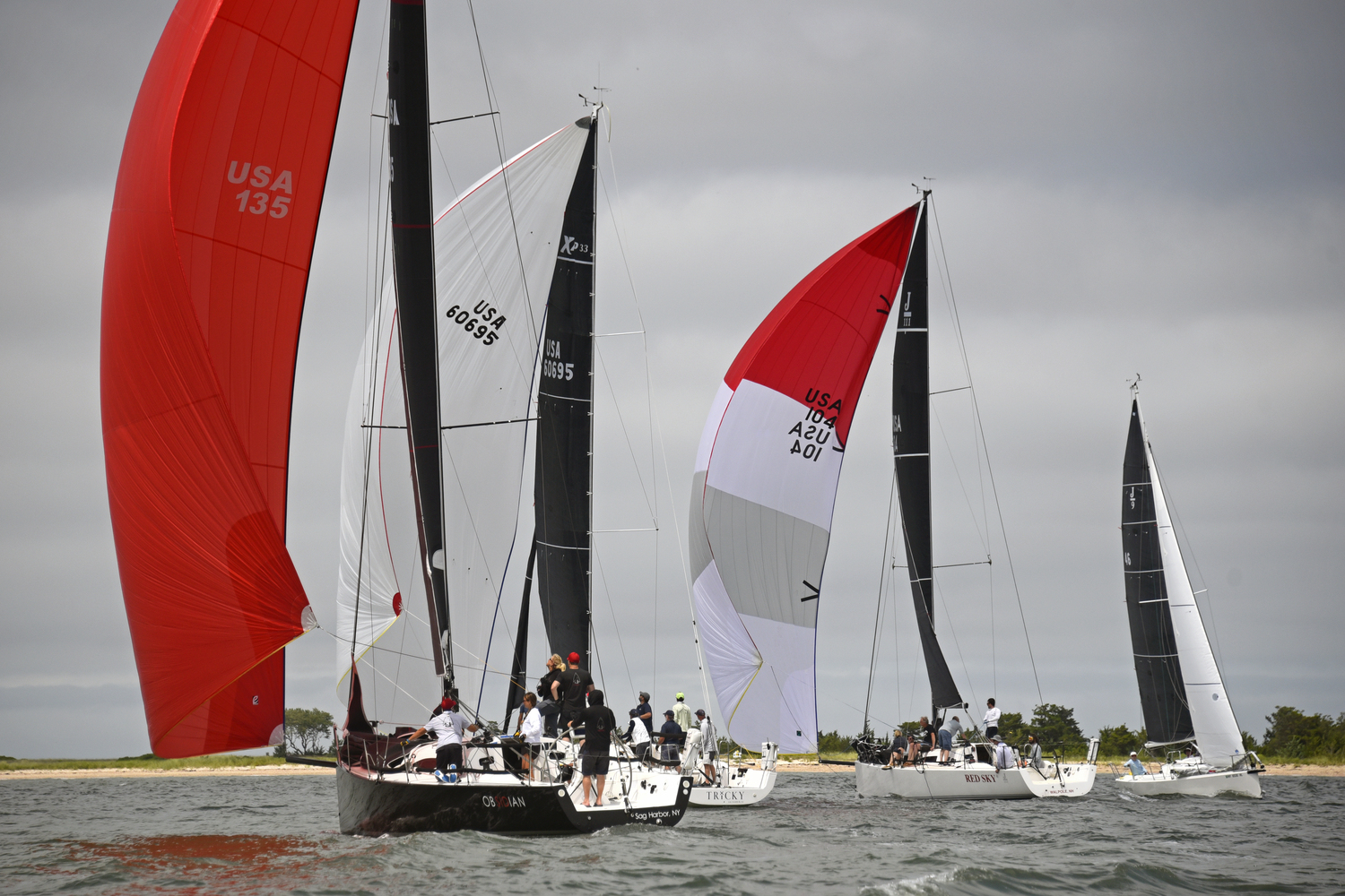 With multiple divisions in this year’s pursuit regatta, oftentimes yachts engaged each other going in opposite directions. From left, Obsidian, Tricky and Red Sky broad-reaching west flying spinnakers along the south shore of Shelter Island, while Richard Bockman’s Gale Force is close-hauled, heading east.  MICHAEL MELLA