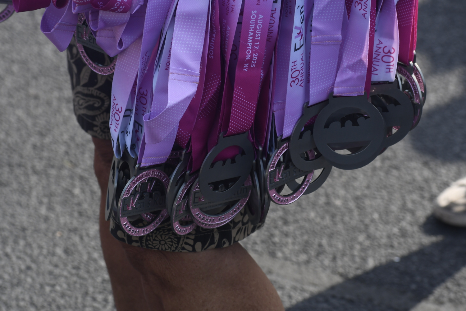 A volunteer holds a stash of medals at the finish line.  DREW BUDD