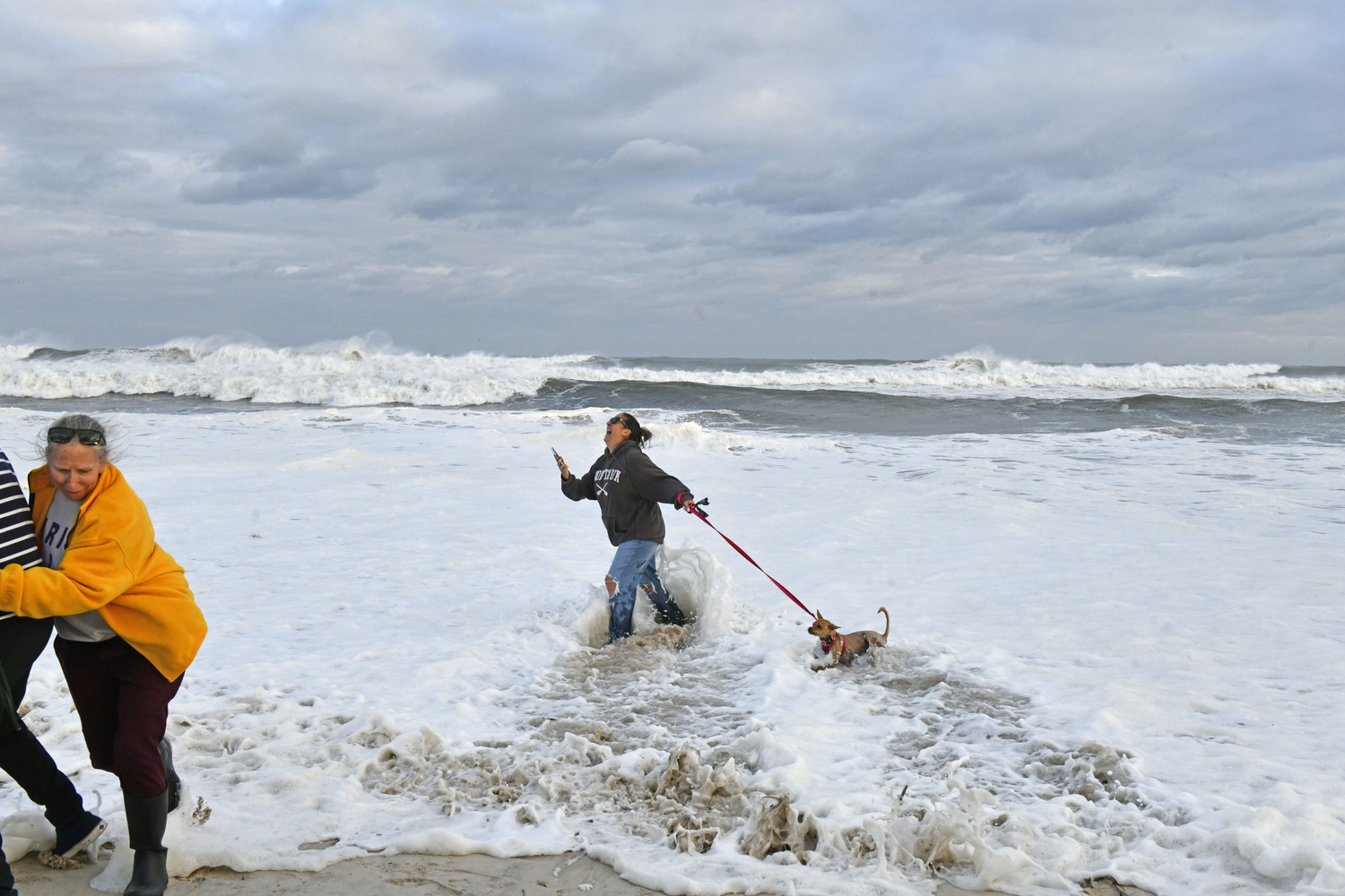Victoria Spinella and her dog, Mila get doused with a wave as the tide comes in at Ponquogue Beach on August 21.  DANA SHAW