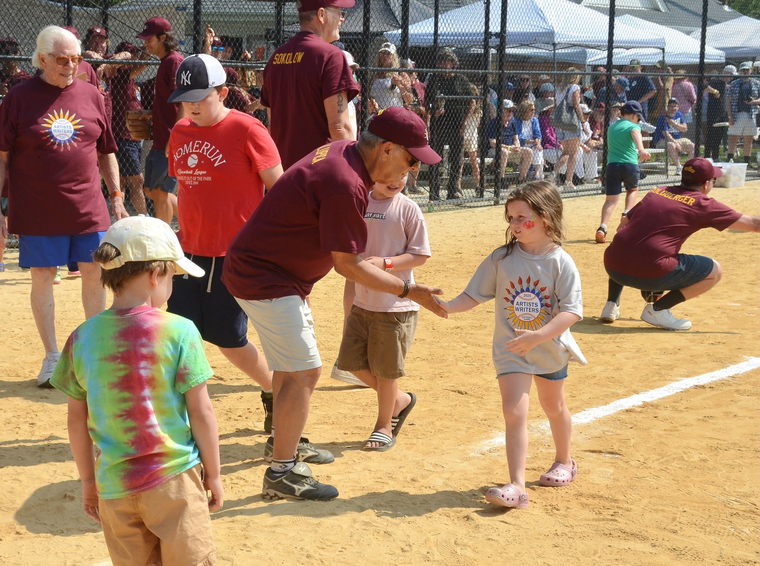 Mike Lupica greets young runners as they reach home plate.  KYRIL BROMLEY