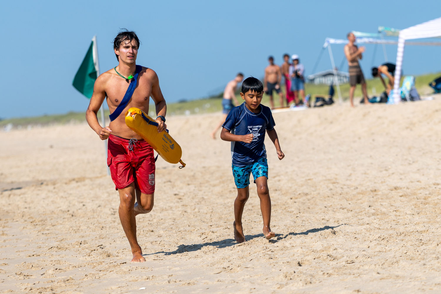 An East Hampton Town lifeguard runs alongside a junior lifeguard.   RON ESPOSITO