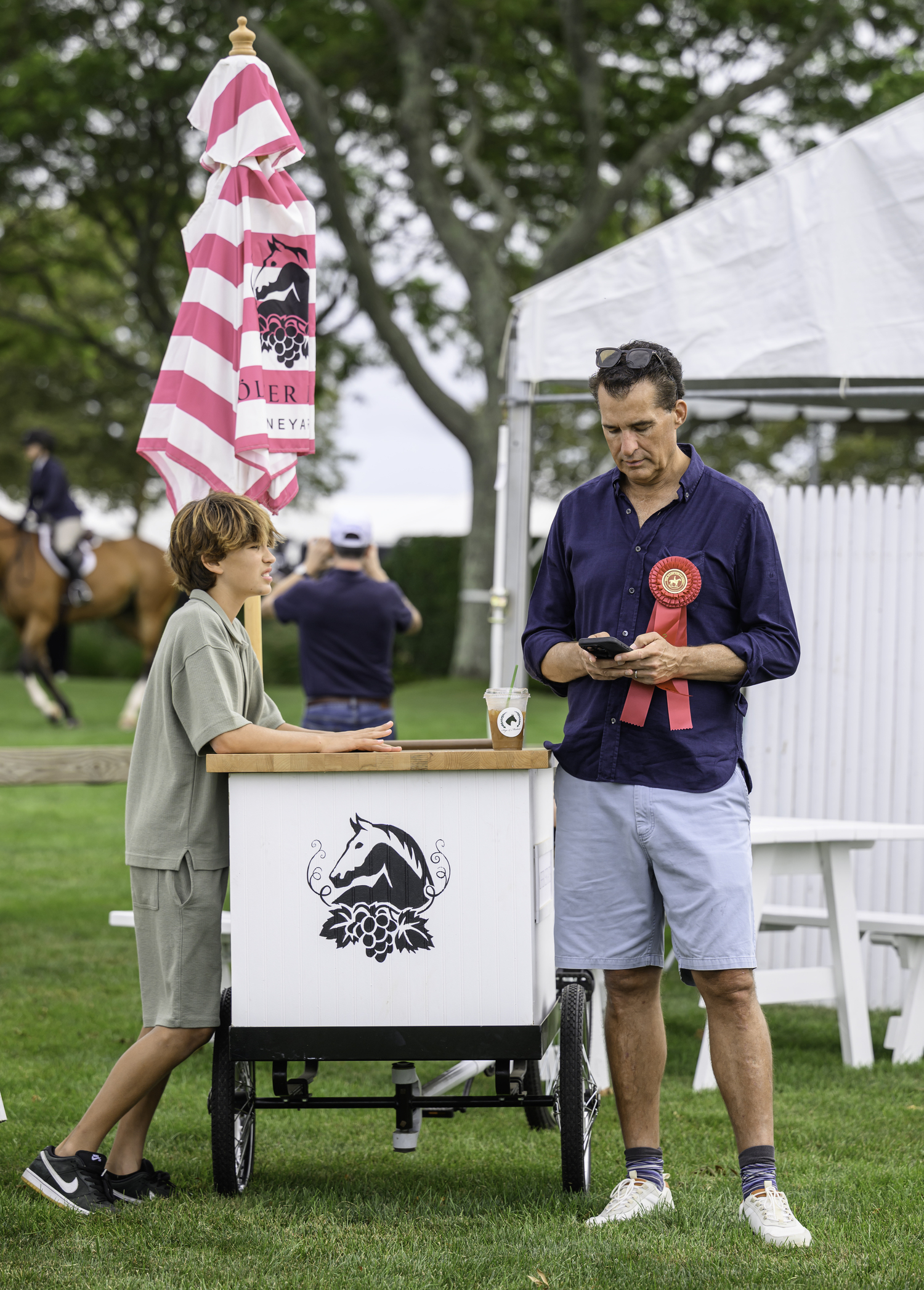 A proud father wearing a child's second place ribbon. Opening Day can be a long one for families waiting for their special ones to ride.  MARIANNE BARNETT