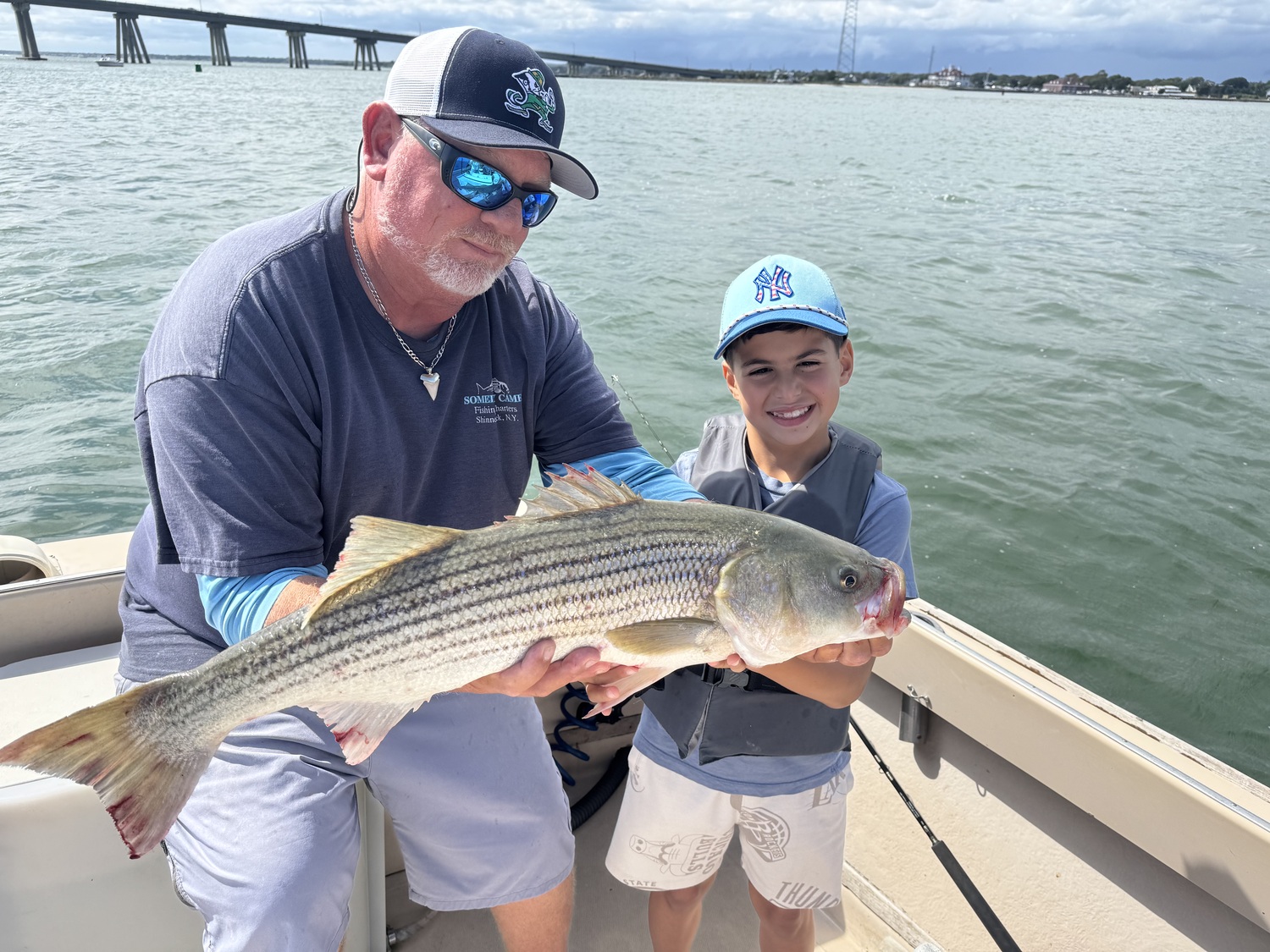 Young angler Simon Yasher got a hand from Capt. Brad Ries hefting the nice slot striper caught while fishing in Shinnecock Bay aboard Someday Came Charters recently.