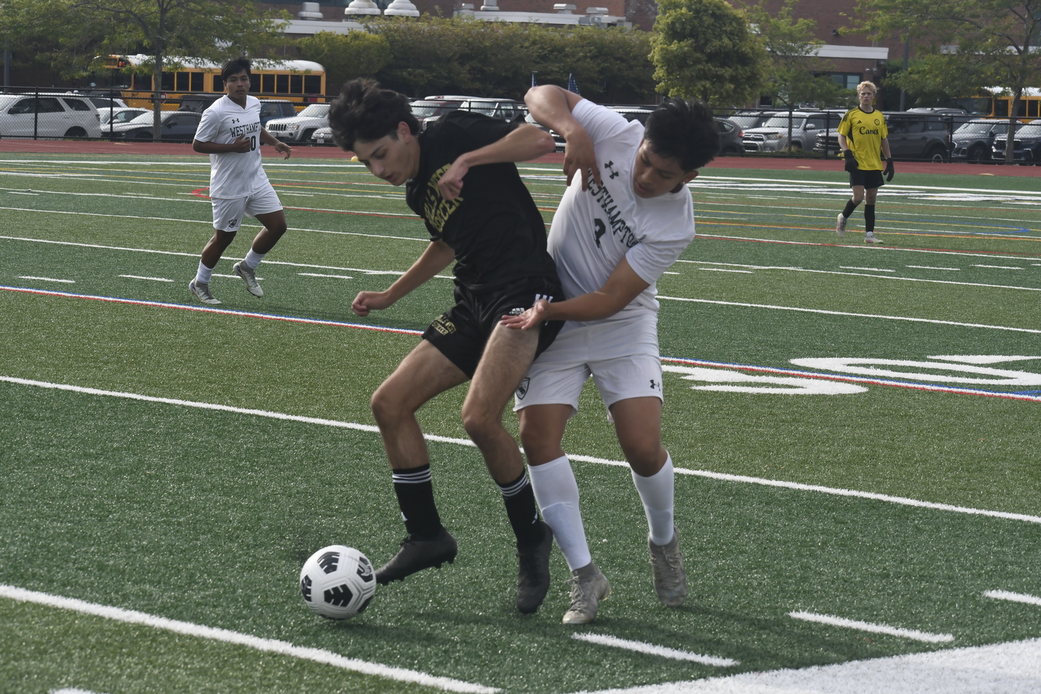Jonathan Chamales battles a Hills West player for the ball.  DREW BUDD