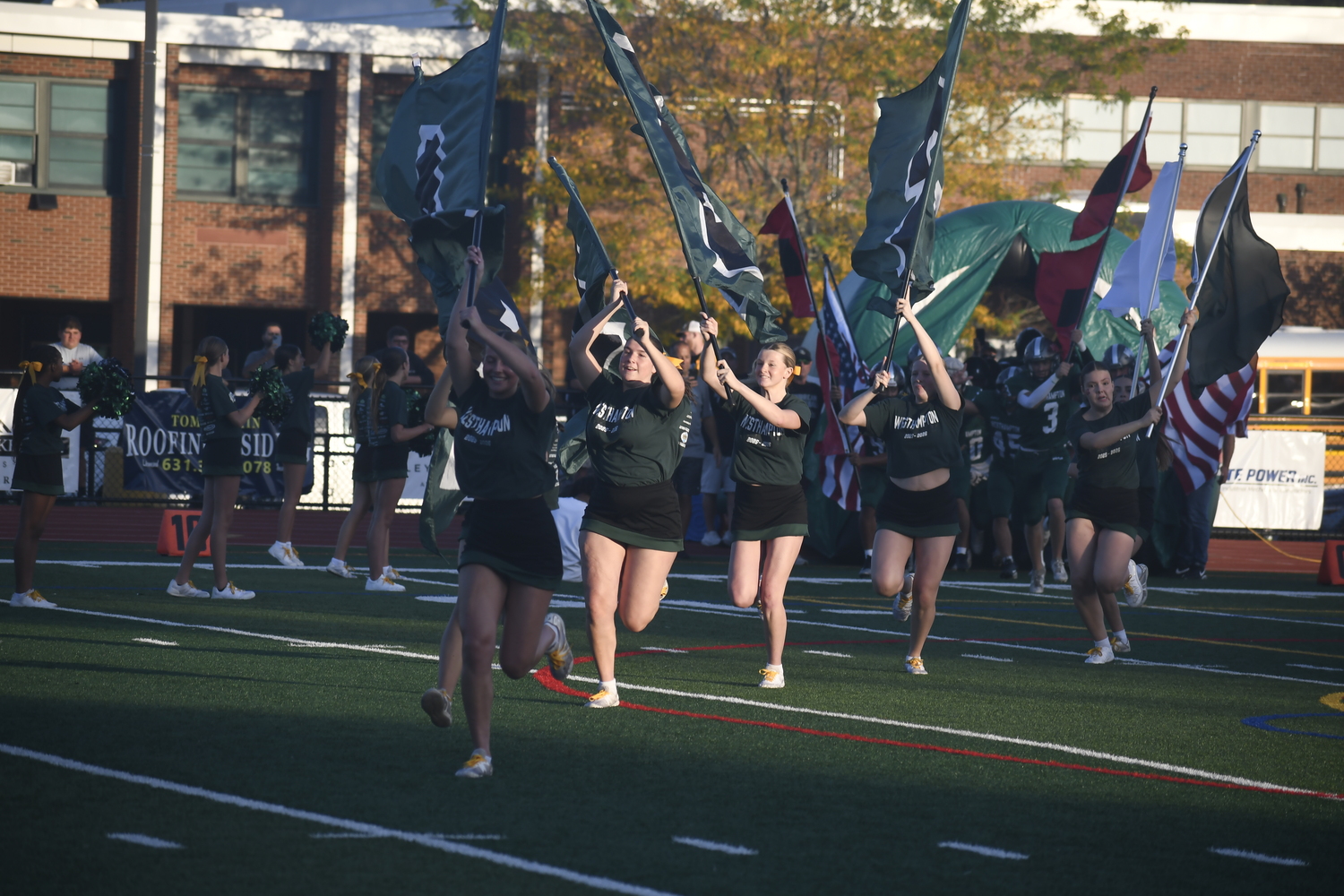 Westhampton Beach varsity cheerleaders lead the football players onto the field prior to Friday night's game.  DREW BUDD