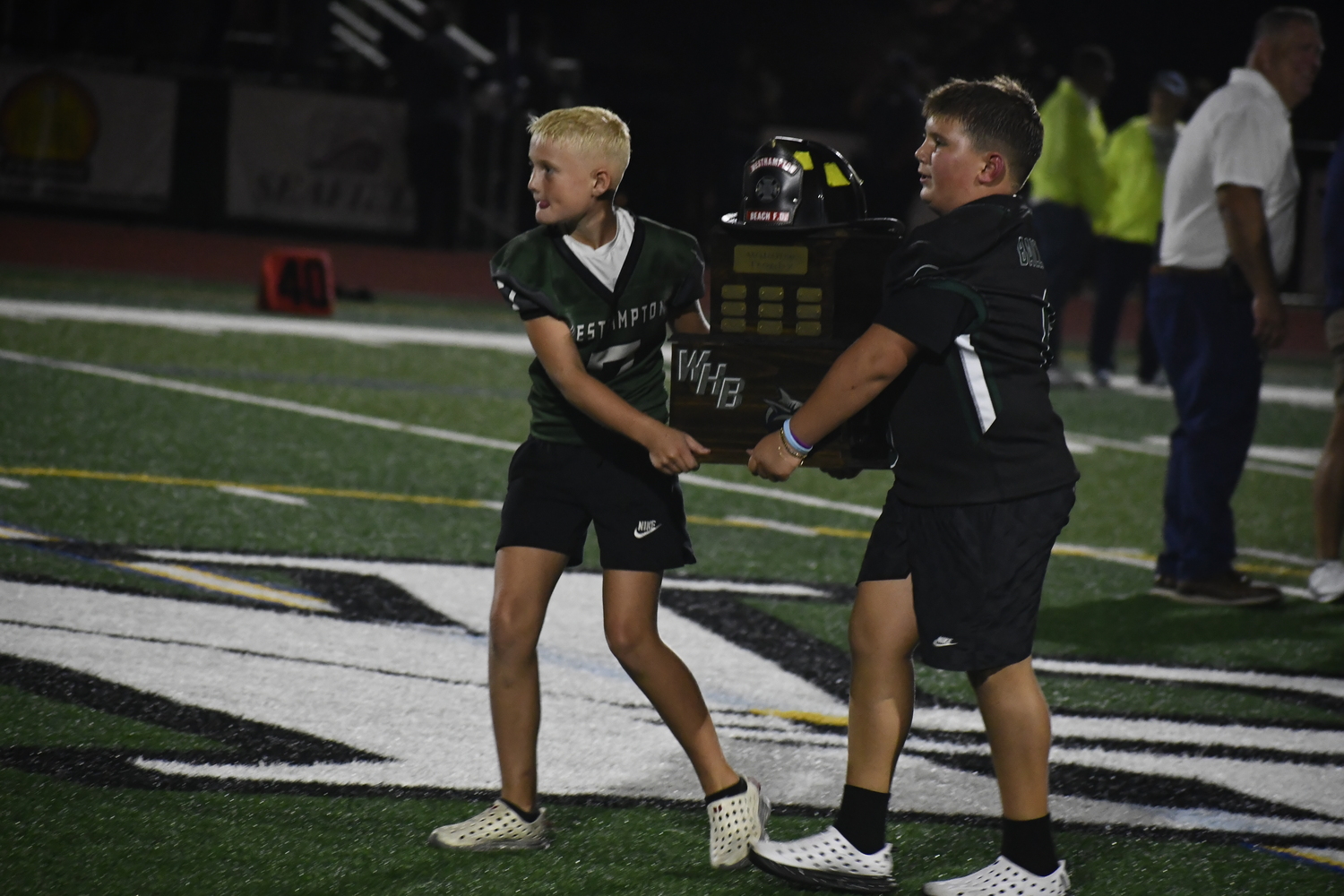 A pair of Westhampton Beach youth football players bring the Firemans Cup over to the team. DREW BUDD