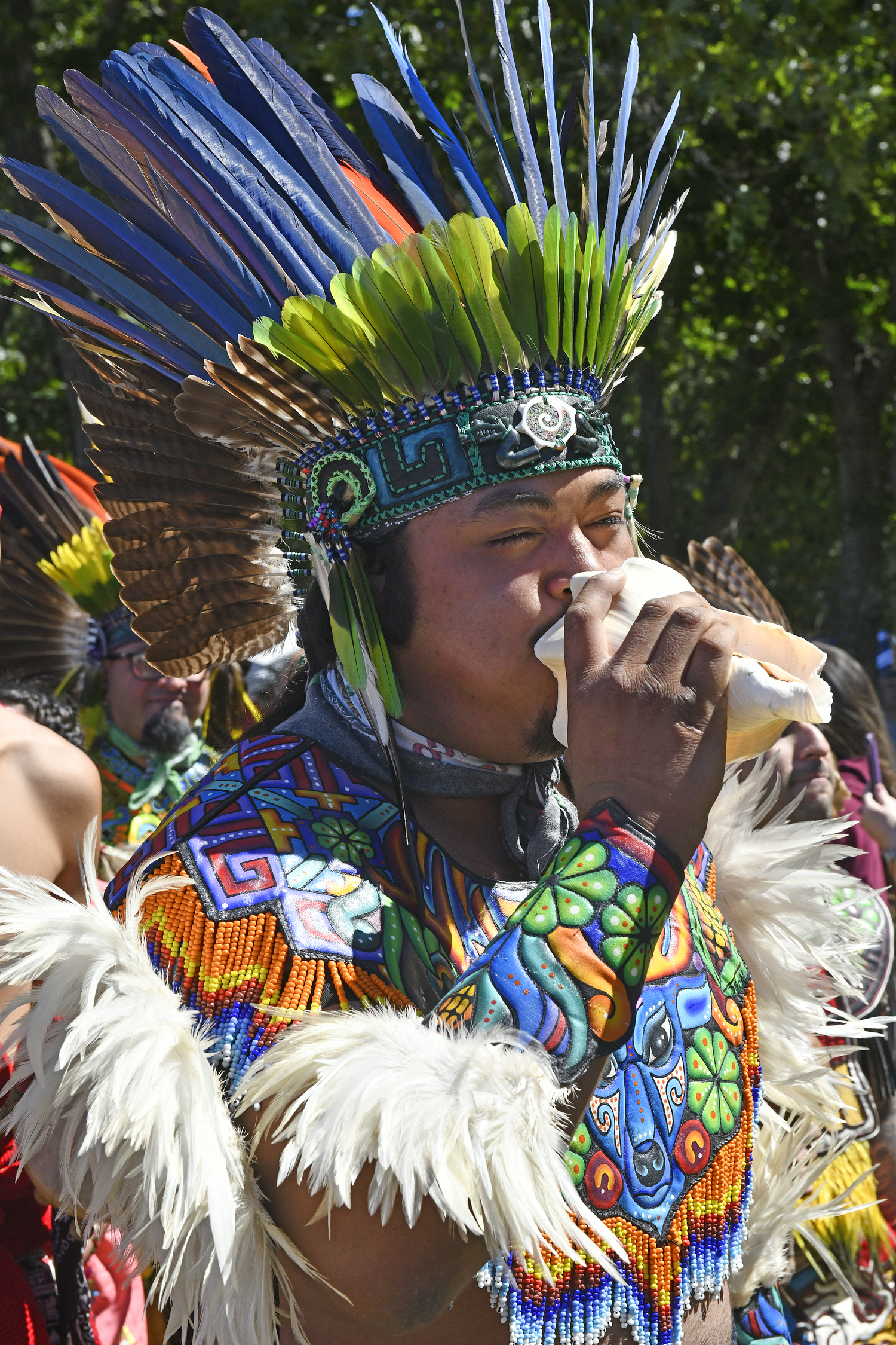 A member of Kalpulli Huehuetlahtolli (Aztec Dancers) sounds a conch shell during the Grand Entry at the 79th annual Shinnecock Powwow.