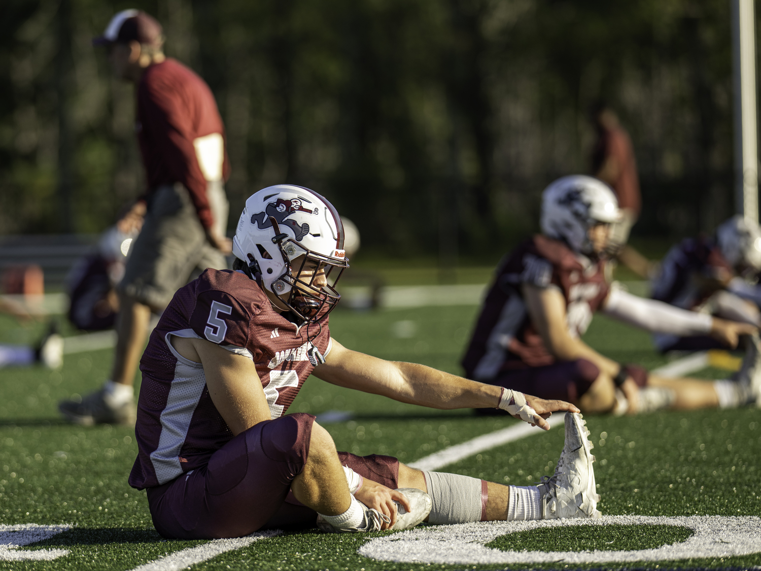 Jackson Ronick and his Bonac teammates stretch on the turf at Stephen Hands Paths prior to their homecoming game on Friday.  MARIANNE BARNETT