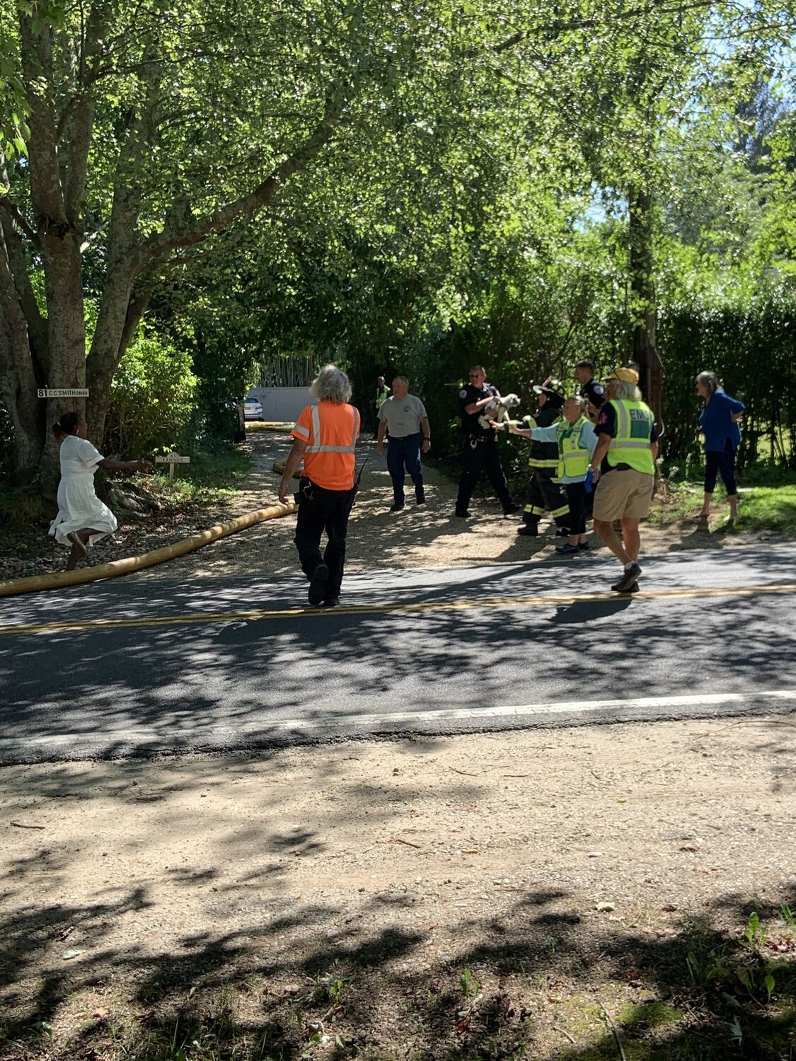 A woman ran to greet the police officer who had emerged with a small dog that had been rescued from a house fire on Hildreth Lane in Bridgehampton on Friday. STEPHEN J. KOTZ