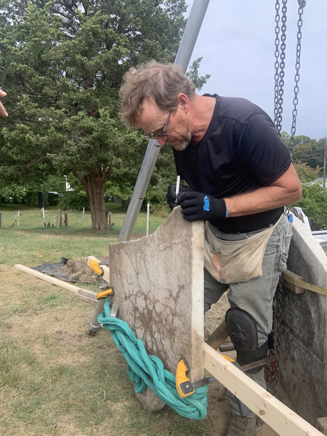 Joel Snodgrass inspects a broken Beebee family headstone in Sag Harbor's Old Burying Ground. STEPHEN J. KOTZ