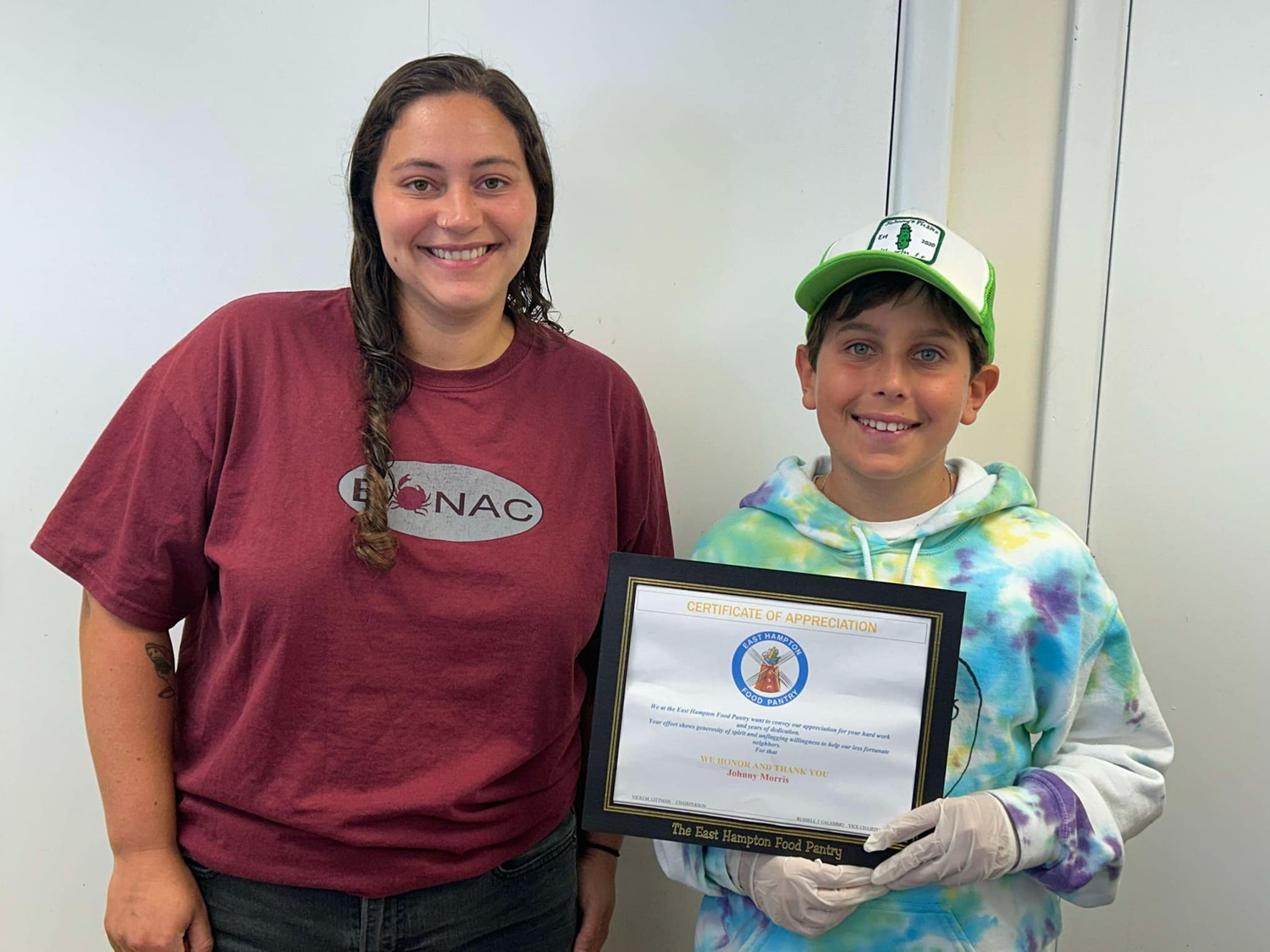 Johnny Morris, 12, of Amagansett and Brooklyn, received a certificate of appreciation for his years of service at the East Hampton Food Pantry. He's been volunteering every summer since 2017. Pantry operations manager Paloma Bahi presented the certificate to Johnny, who has donated proceeds from the pickle stand he runs each summer. COURTESY EAST HAMPTON FOOD PANTRY