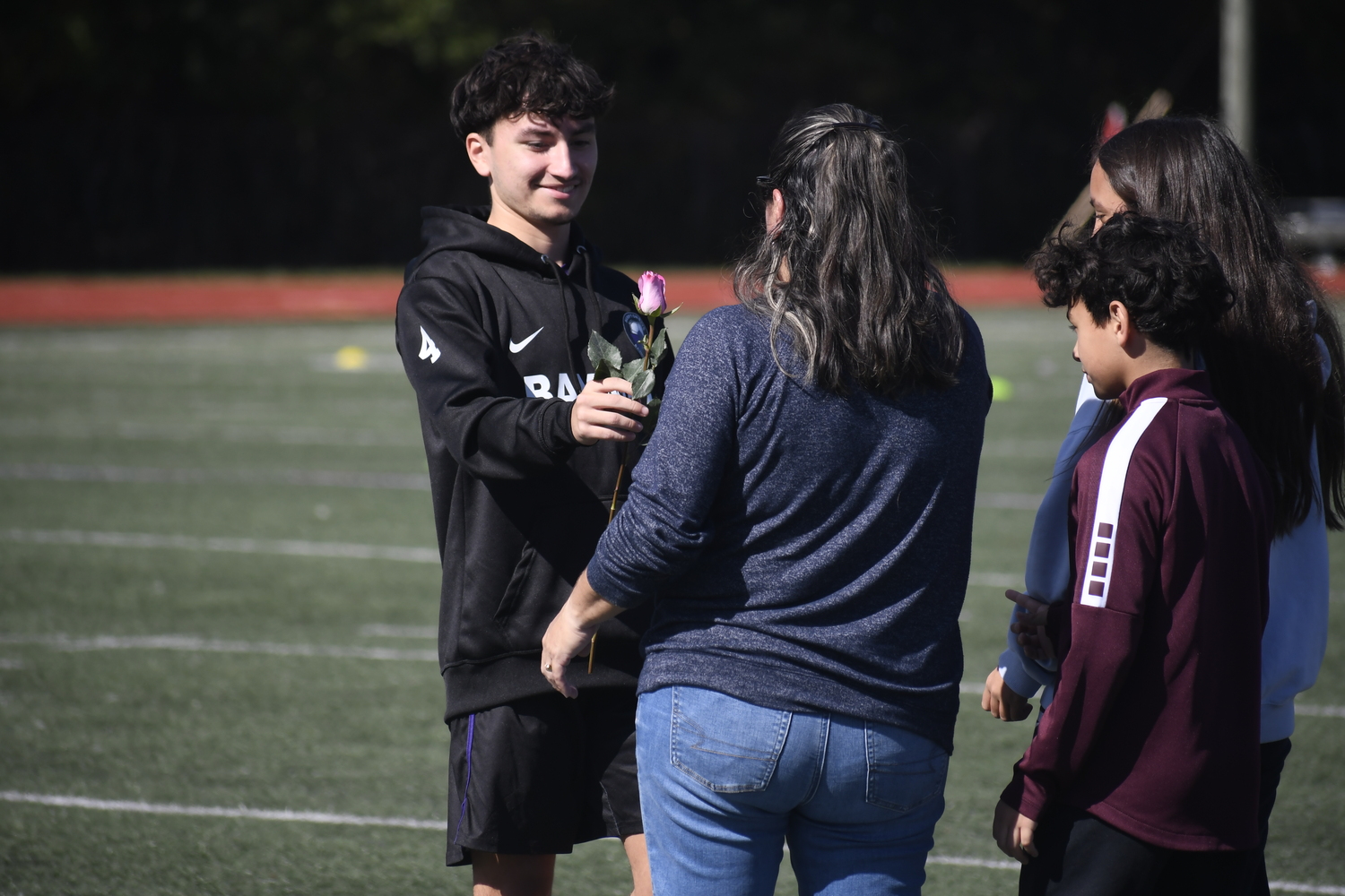 Brandon Guevara hands a rose to his mother and family as part of Saturday's pregame ceremony.  DREW BUDD