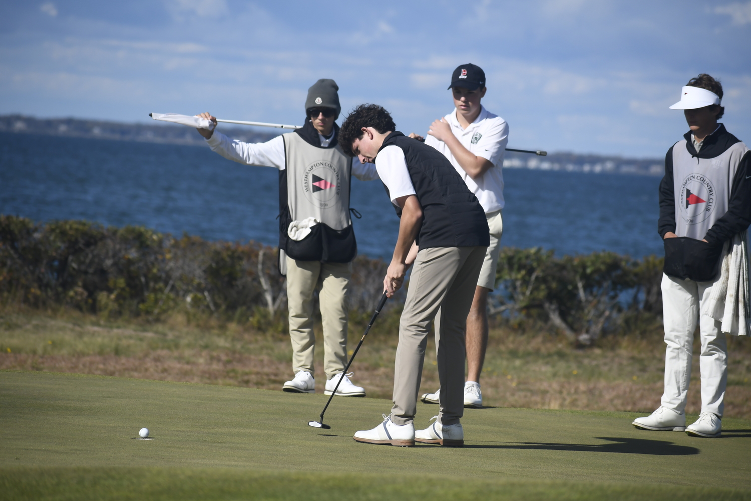 Danny Schumacher putts with his Hurricane teammates watching.  DREW BUDD