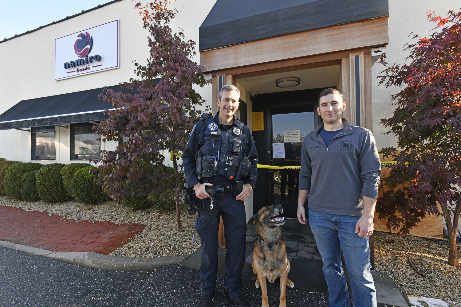 Southampton Village Police Officer James Moore and Southampton fire Department Assistant Chief Kenny Lockard, a village resident who also happens to be a co-owner of Namiro, with Topper in front of the restaurant on Wednesday morning.  DANA SHAW