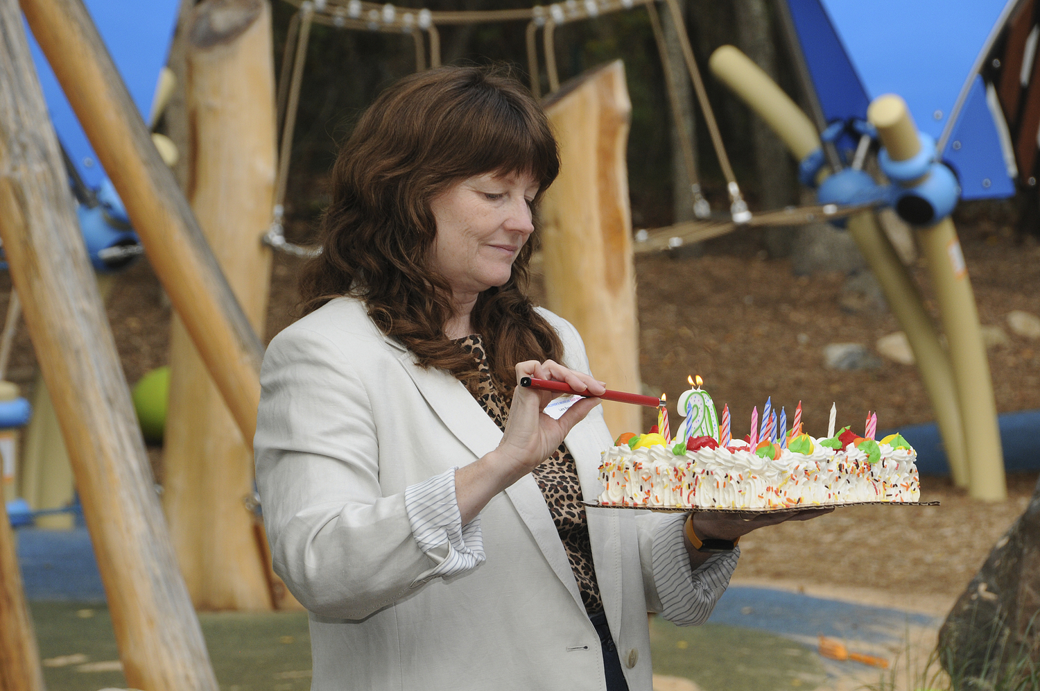 Lara Sweeney, co-president of the Children's Museum of the East End, lights the candles on the cake at the 20th anniversary celebration on Saturday at the museum.  RICHARD LEWIN