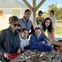 Group for the East End's Assistant Director of Environmental Education Jen Skilbred, left, with students looking at treasures they found at Maidstone Beach. COURTESY GROUP FOR THE EAST END