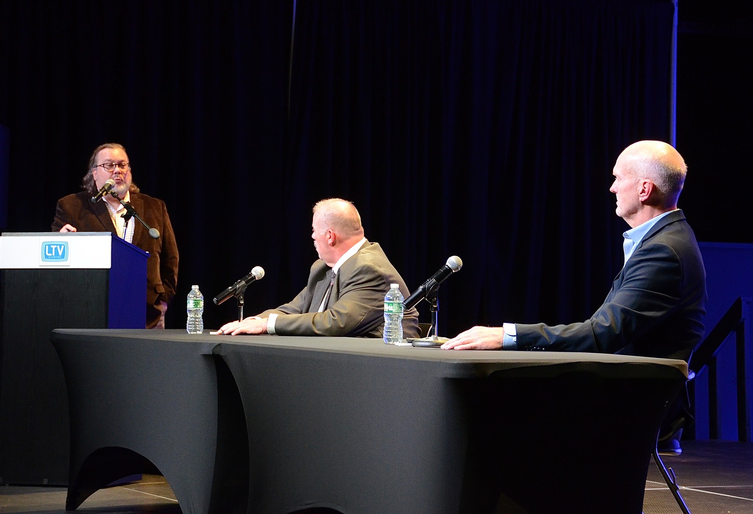 The two candidates for East Hampton Town Clerk, Jeff Miller, seated left, and Michael Hansen, seated right, wait for a question from Express News Group Executive Editor Joe Shaw, who moderated the debate on Monday night. KYRIL BROMLEY